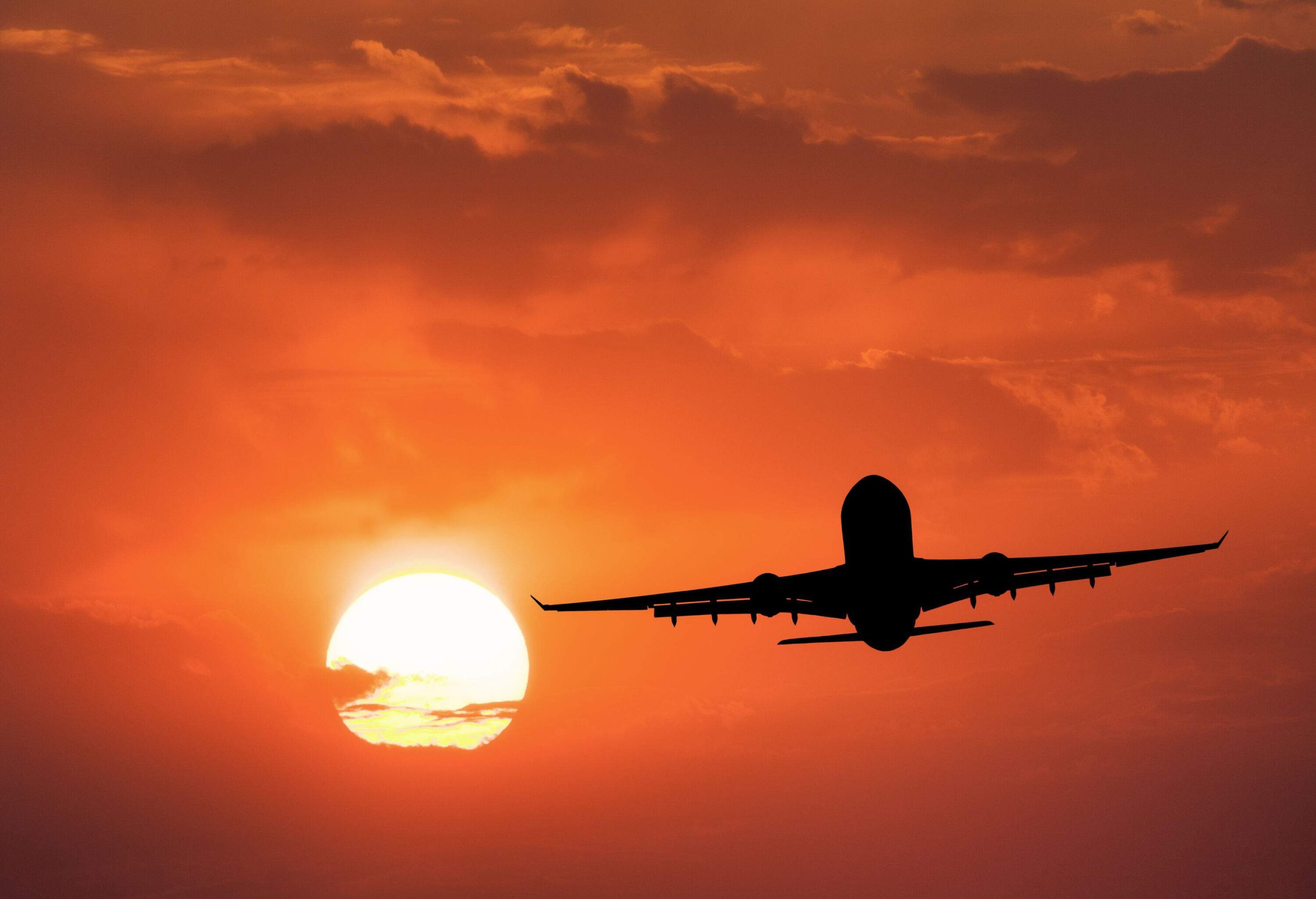 Silhouette of an aircraft against the backdrop of scenic red sunset sky. 