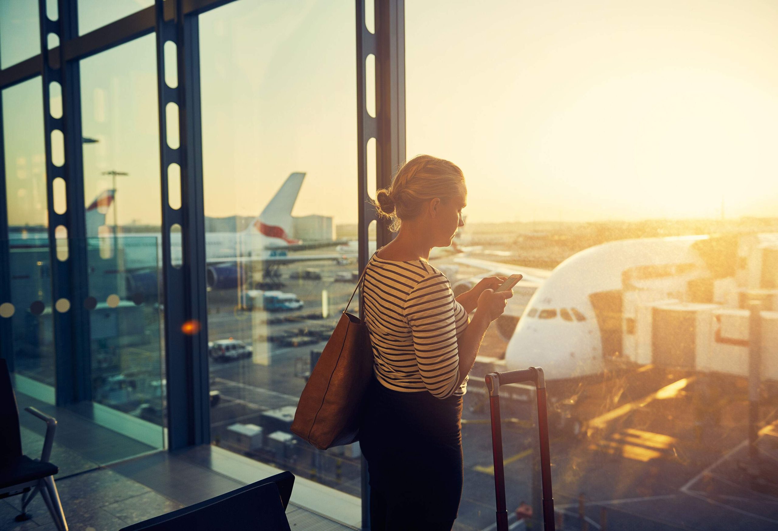 A young woman, engrossed in her cellphone, glared through the window of an airport departure lounge.