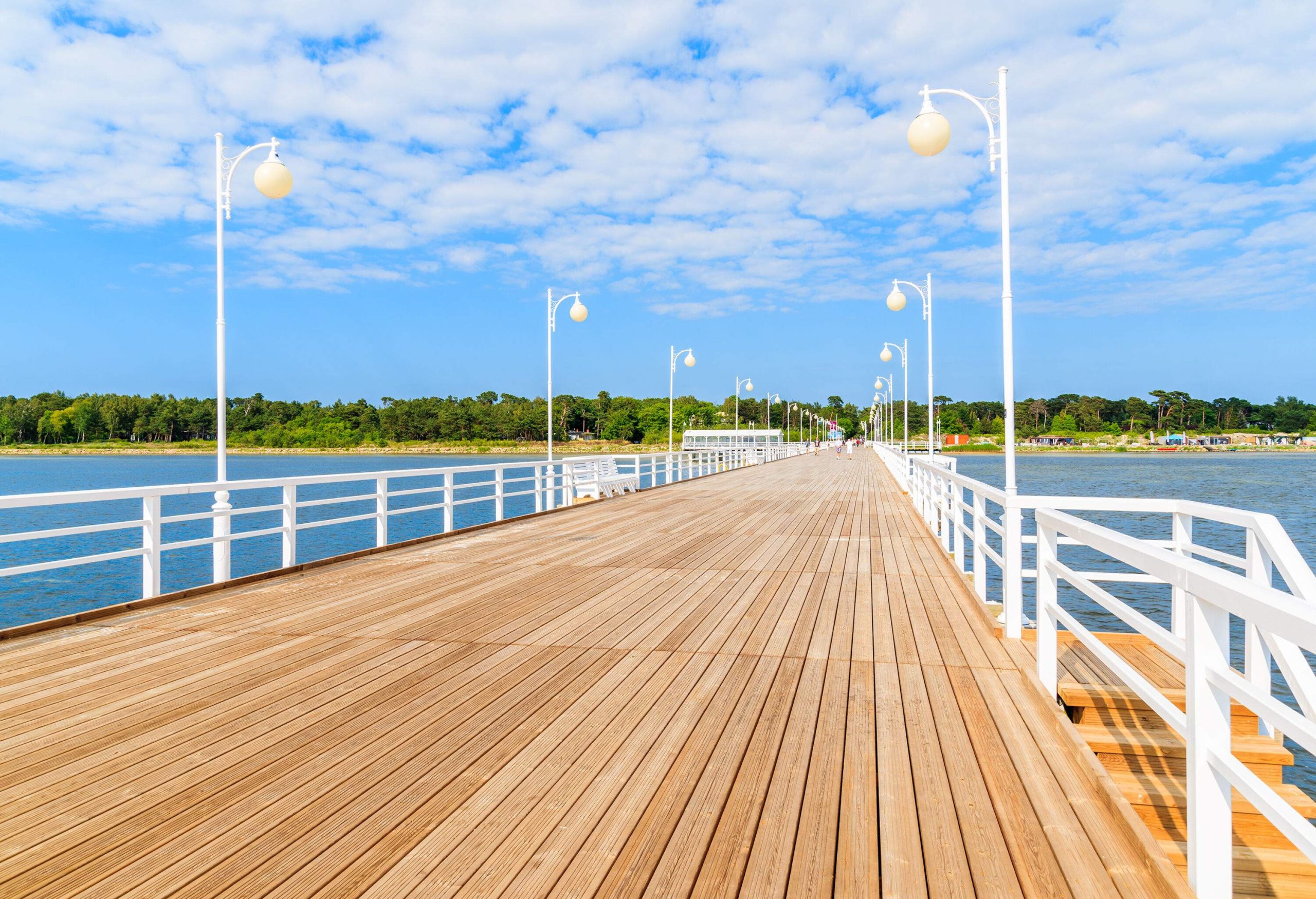 A wooden pier lined with streetlamps across the sea.