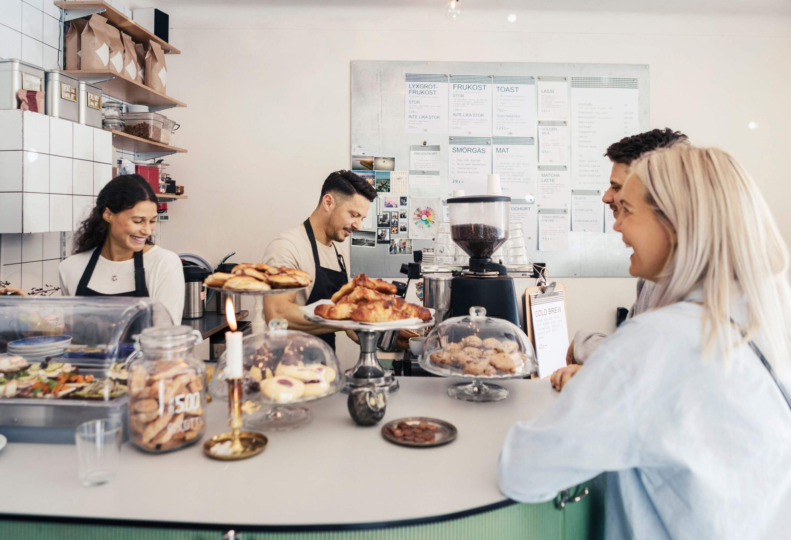 Food servers and customers giggle together inside a cafe.