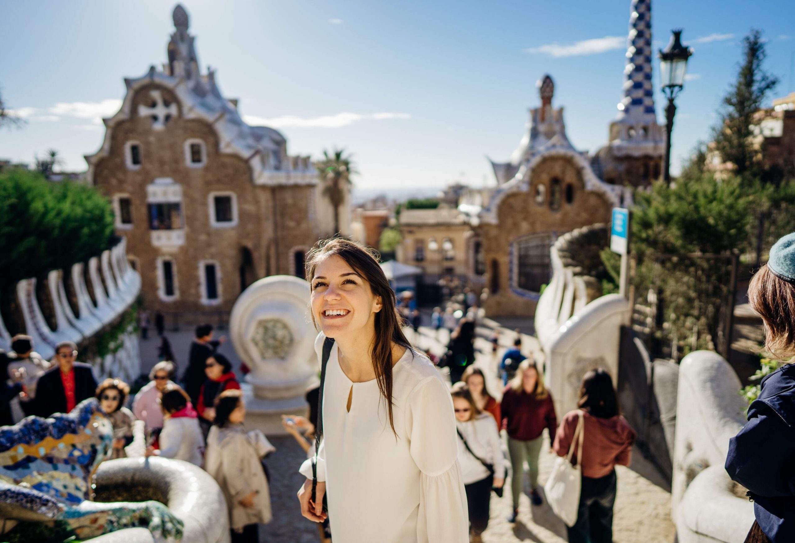 A woman standing in the middle of a street smiling as she looks up at something.