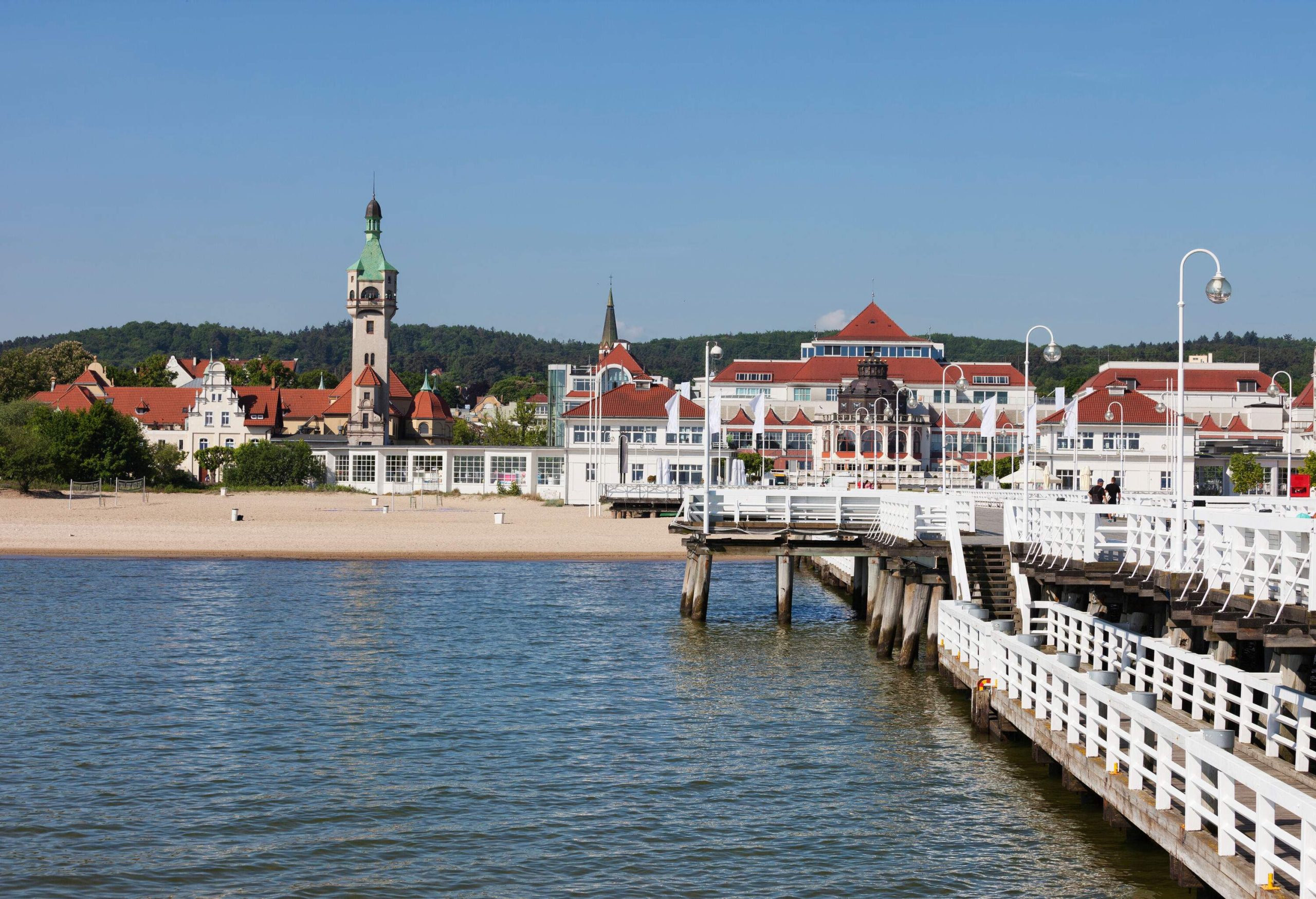 A shore lined with castle-like buildings with a wooden pier over the sea.