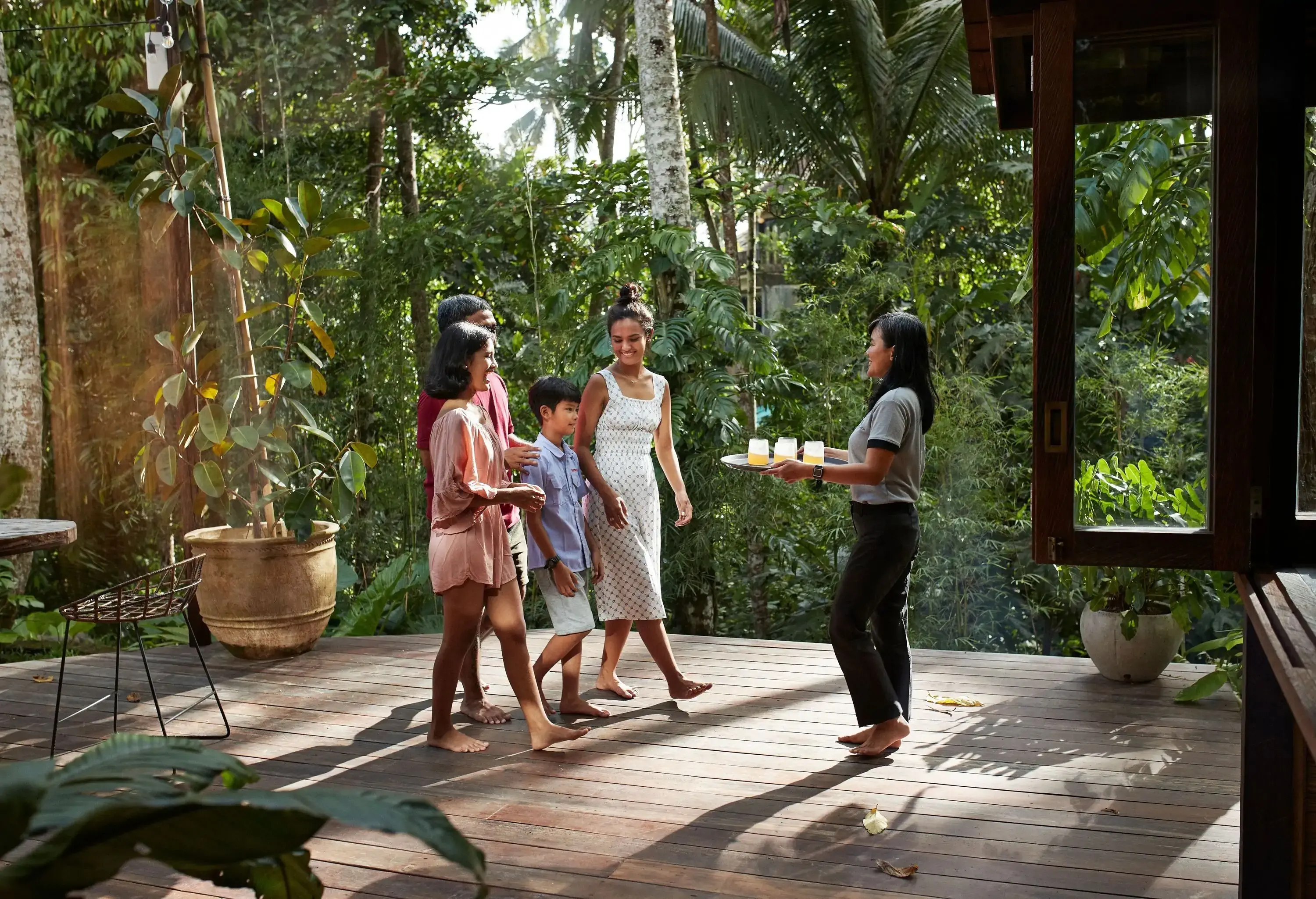 Family walking towards waitress standing with welcome drinks at resort during vacation