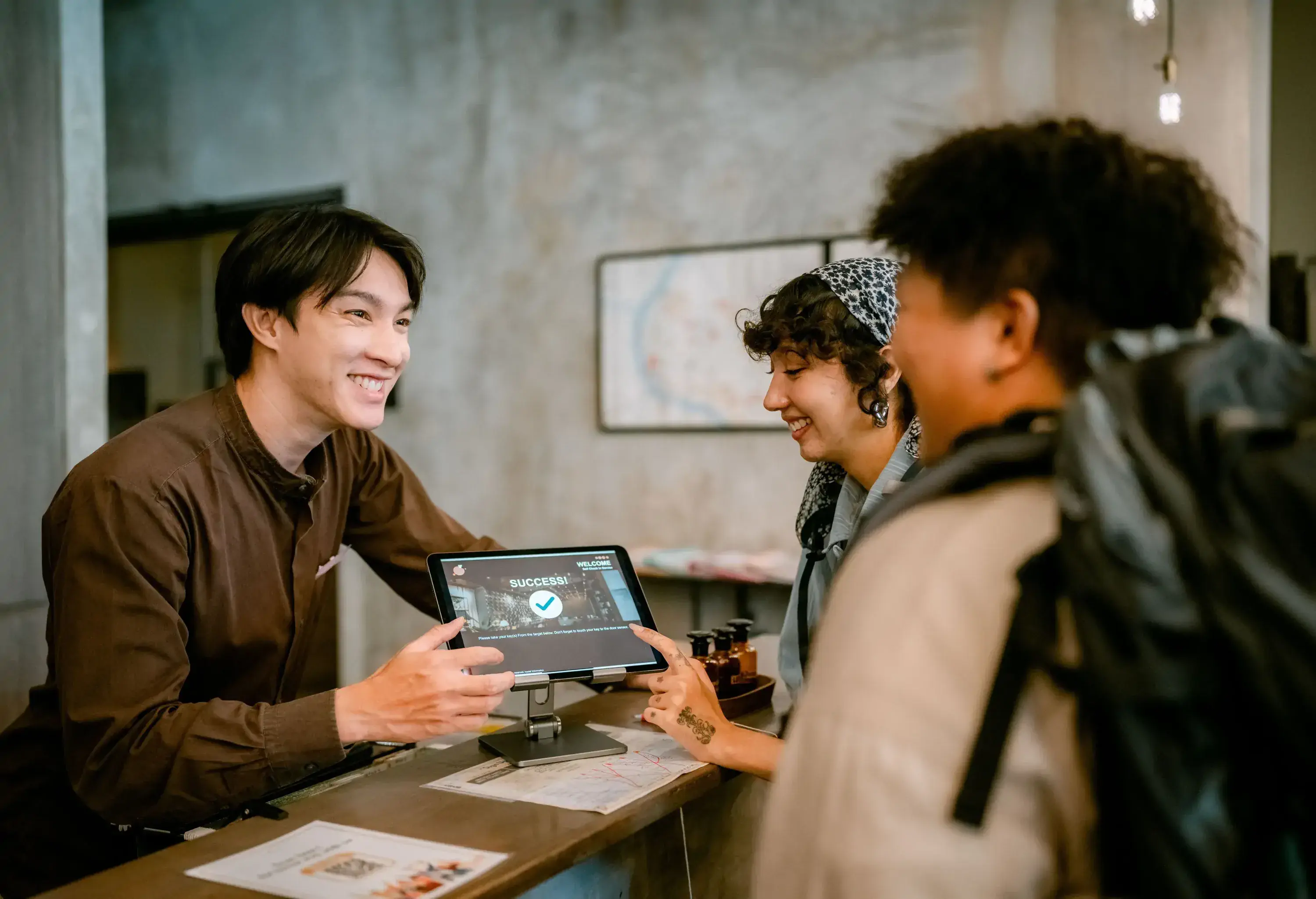Two backpackers arriving and registering with a digital tablet at reception.