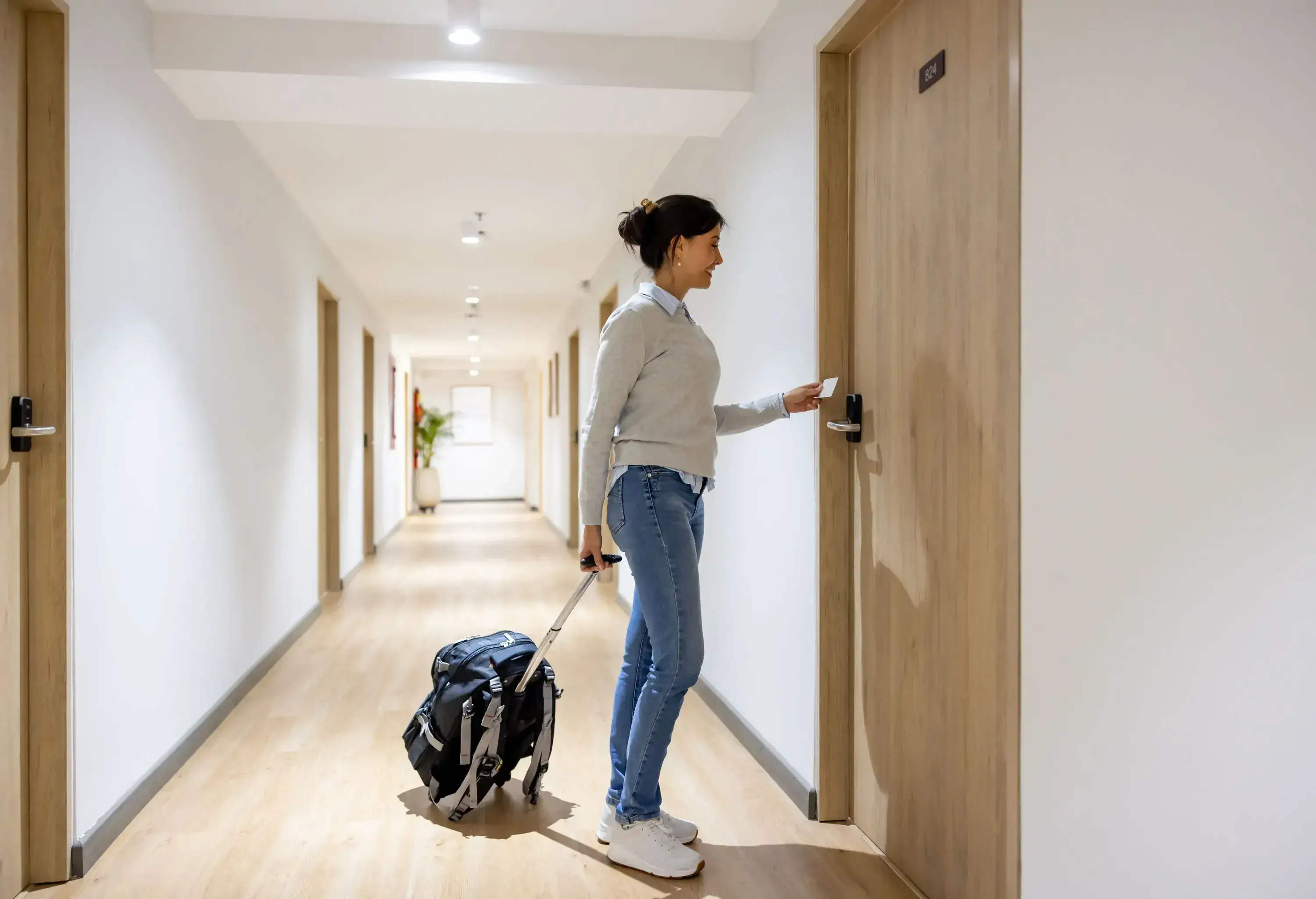 Latin American woman traveling and entering her room at a hotel - travel concepts
