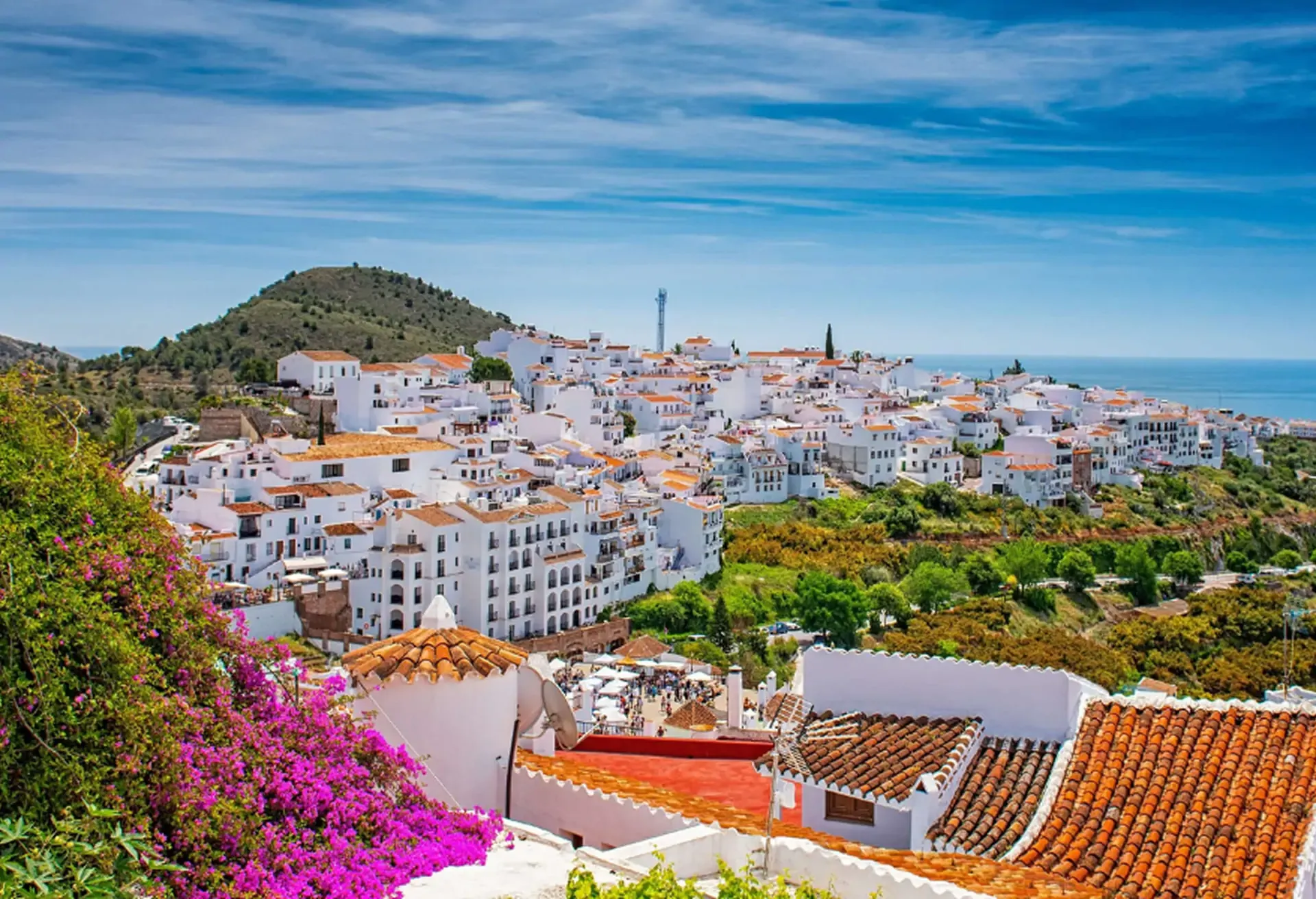 Panoramic view of a picturesque Spanish white village on a hillside overlooking the blue sea.