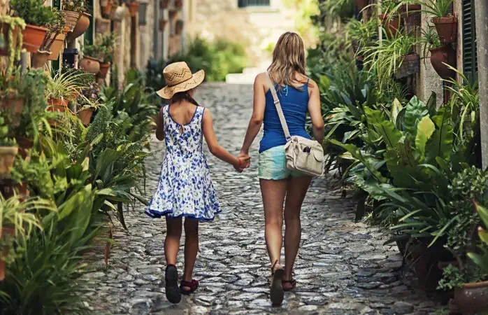 Mother and daughter walking beautiful street of a mediterranean town. Valldemossa, Mallorca, Spain. Slightly soft.