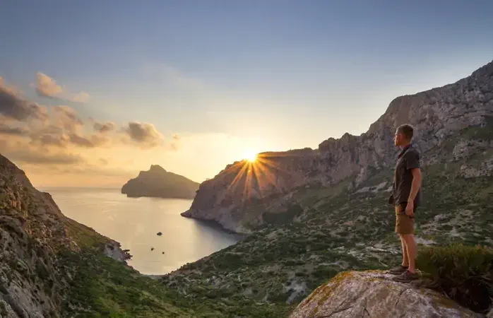Incredible sunrise over Cap de Formentor and Cala Bóquer near Pollenca, Mallorca, Spain with a man on rock watching sunrise high above sea level; Shutterstock ID 1169584342; Brand (KAYAK, Momondo, Any): Any