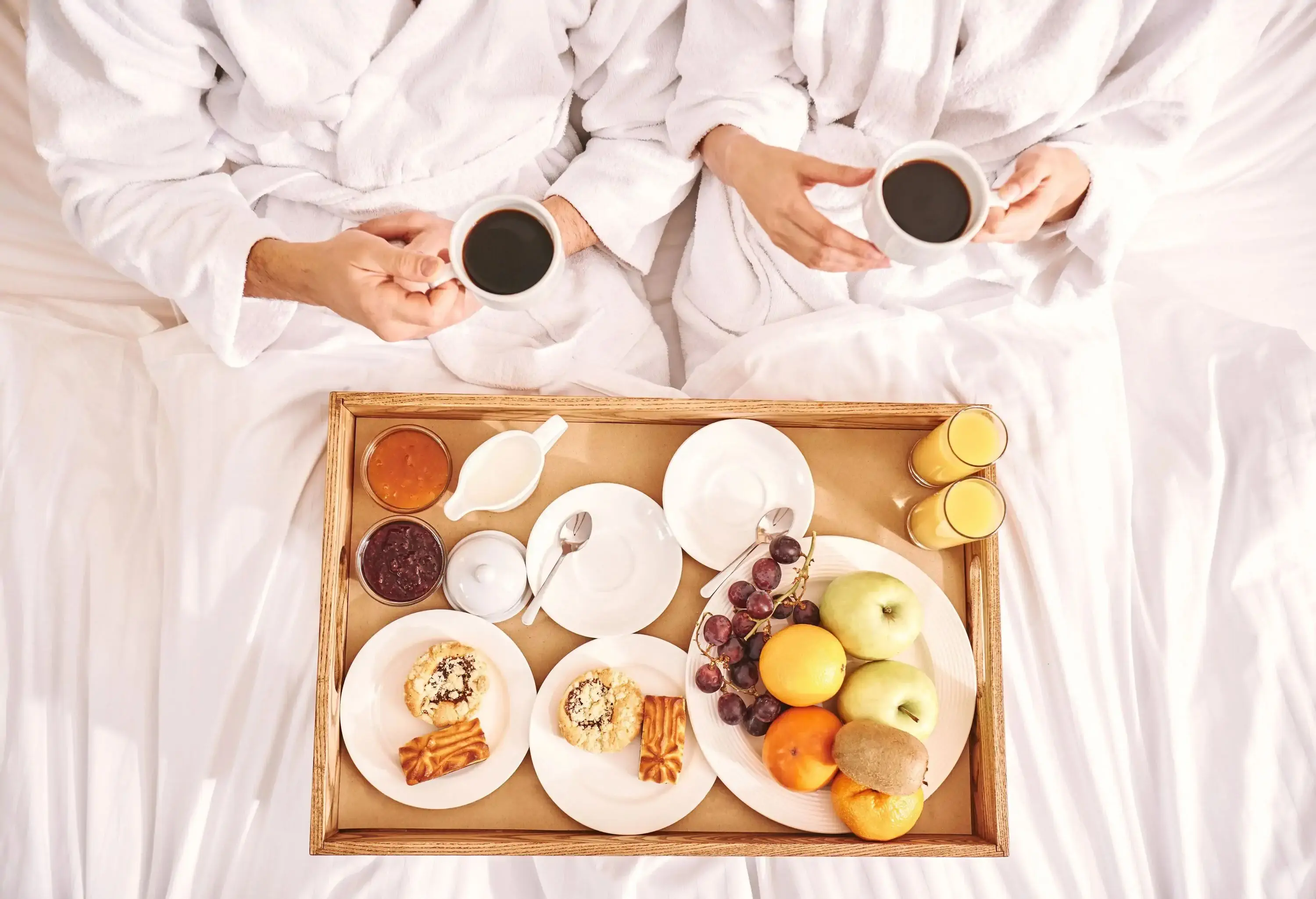 Fresh breakfast in room. Close-up of couple are eating in hotel room bed together, Top view