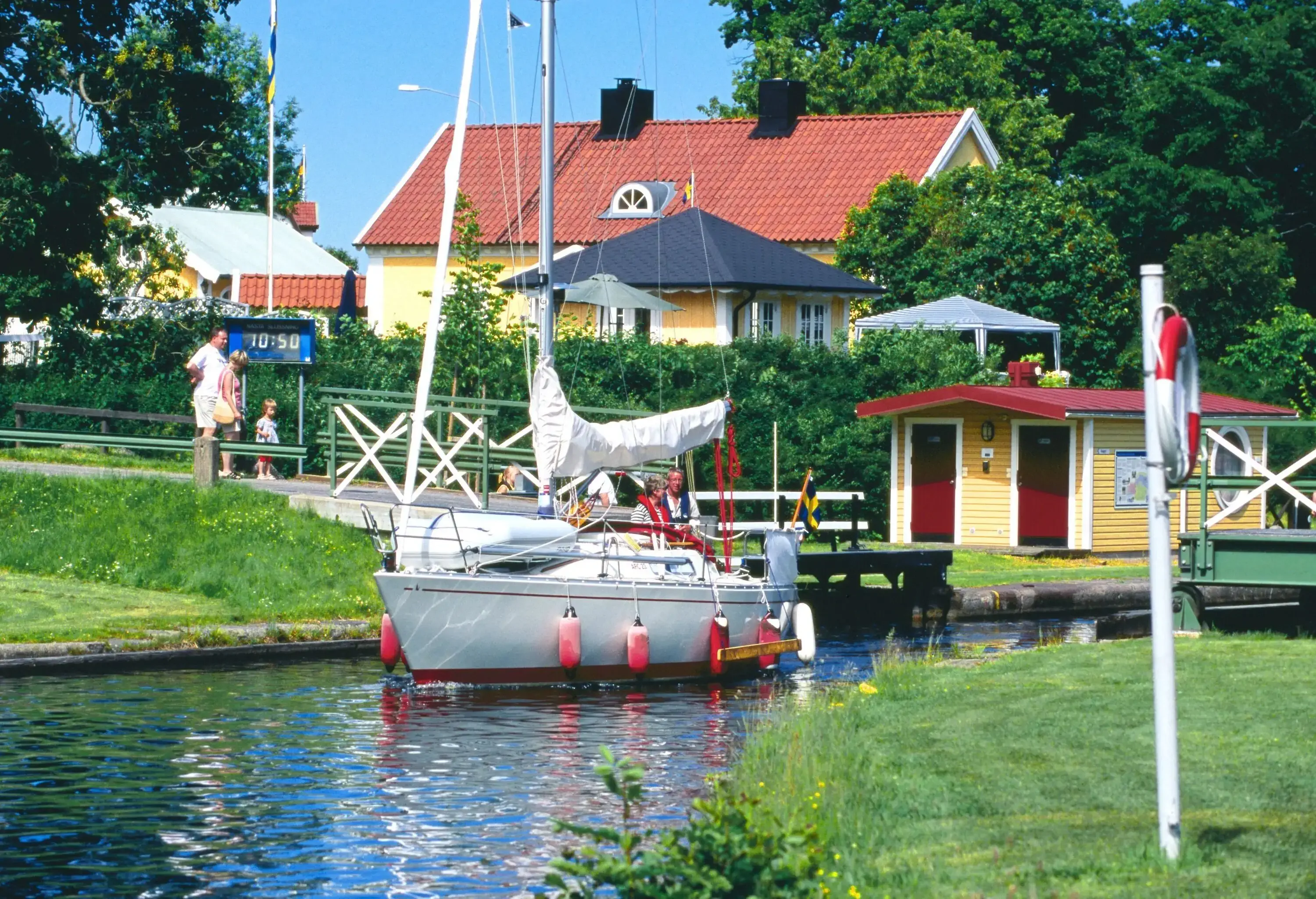 A small sailboat on a canal by yellow buildings