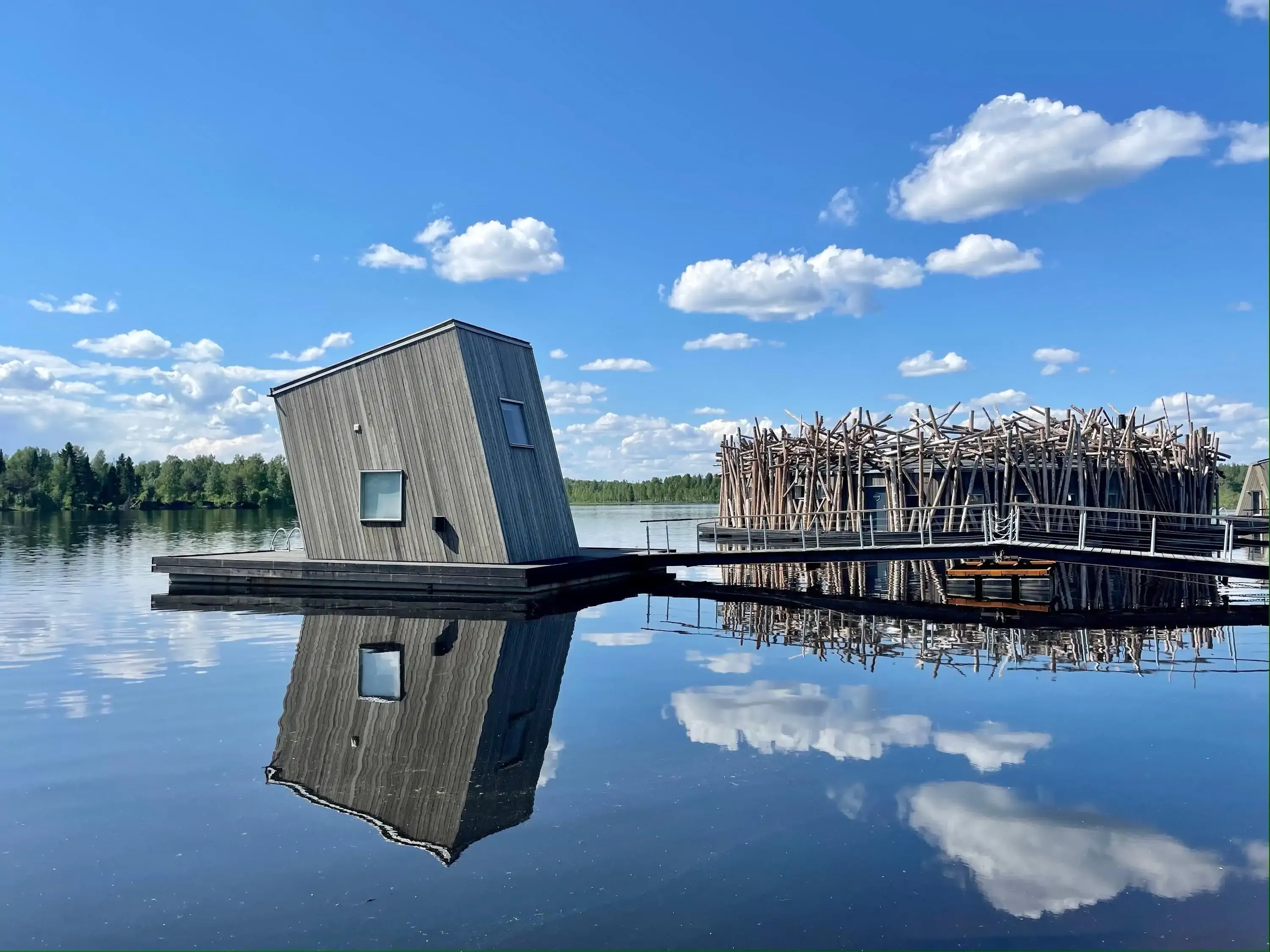 View of modern hotel wooden structure reflected on a lake on a sunny day