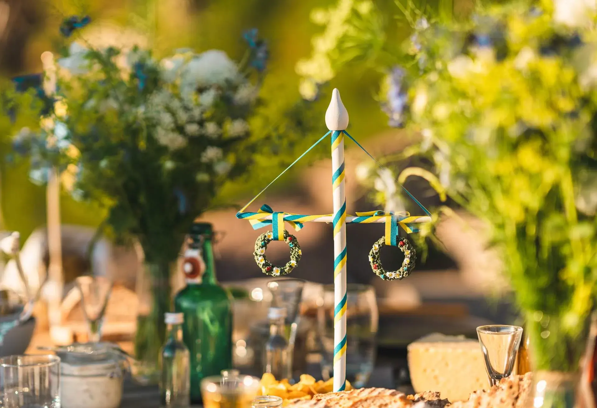 A traditional Swedish maypole decoration on the table at midsummer. Surrounded by food and flowers.