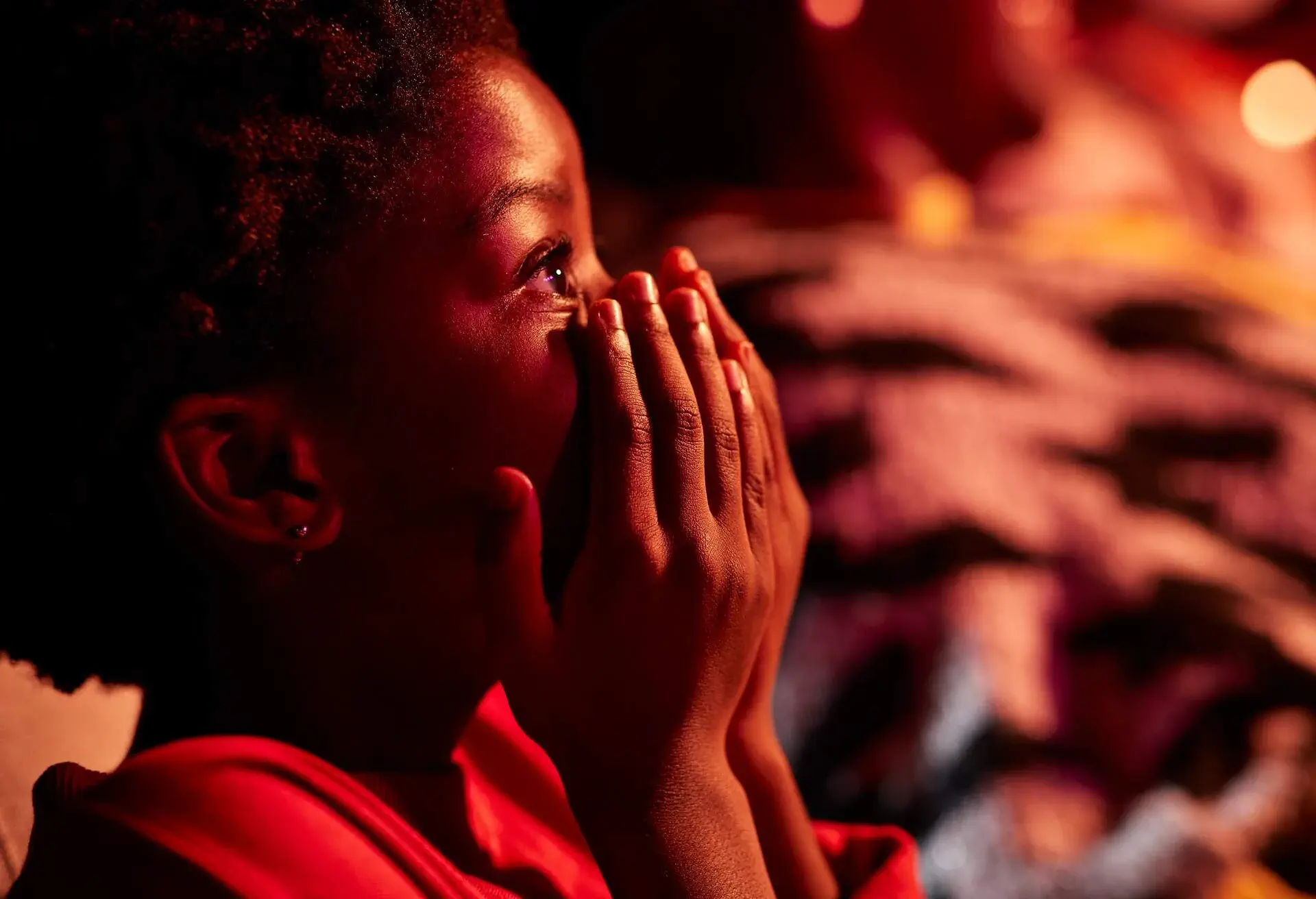 Side view of shocked girl covering mouth in movie theater
