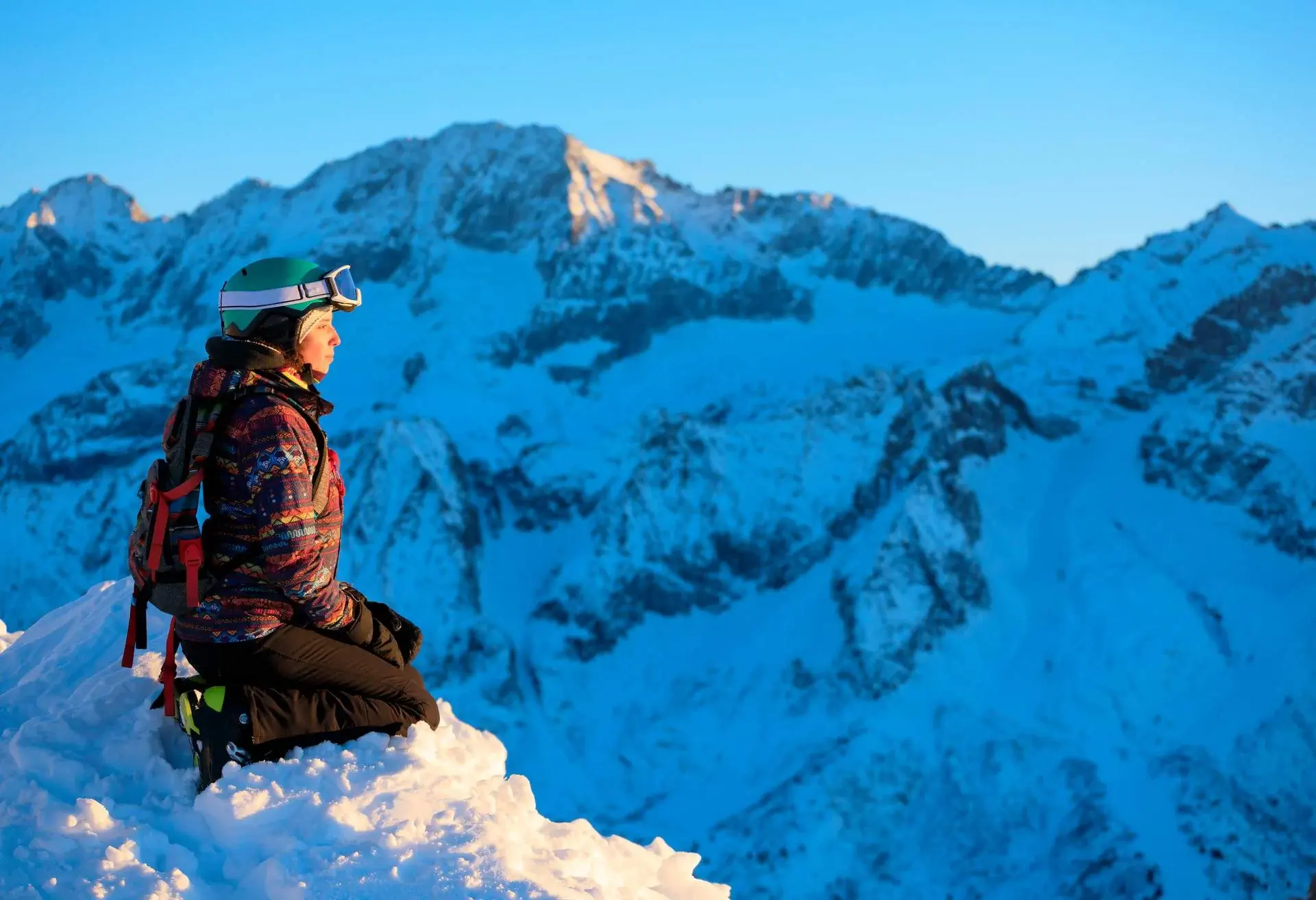 Woman skier enjoys, in a beautiful view at sunny ski resort Amateur Winter Sports. Sunset On the top. High mountain snowy landscape. Italian Alps mountain of the Dolomites Passo Tonale, Italy.