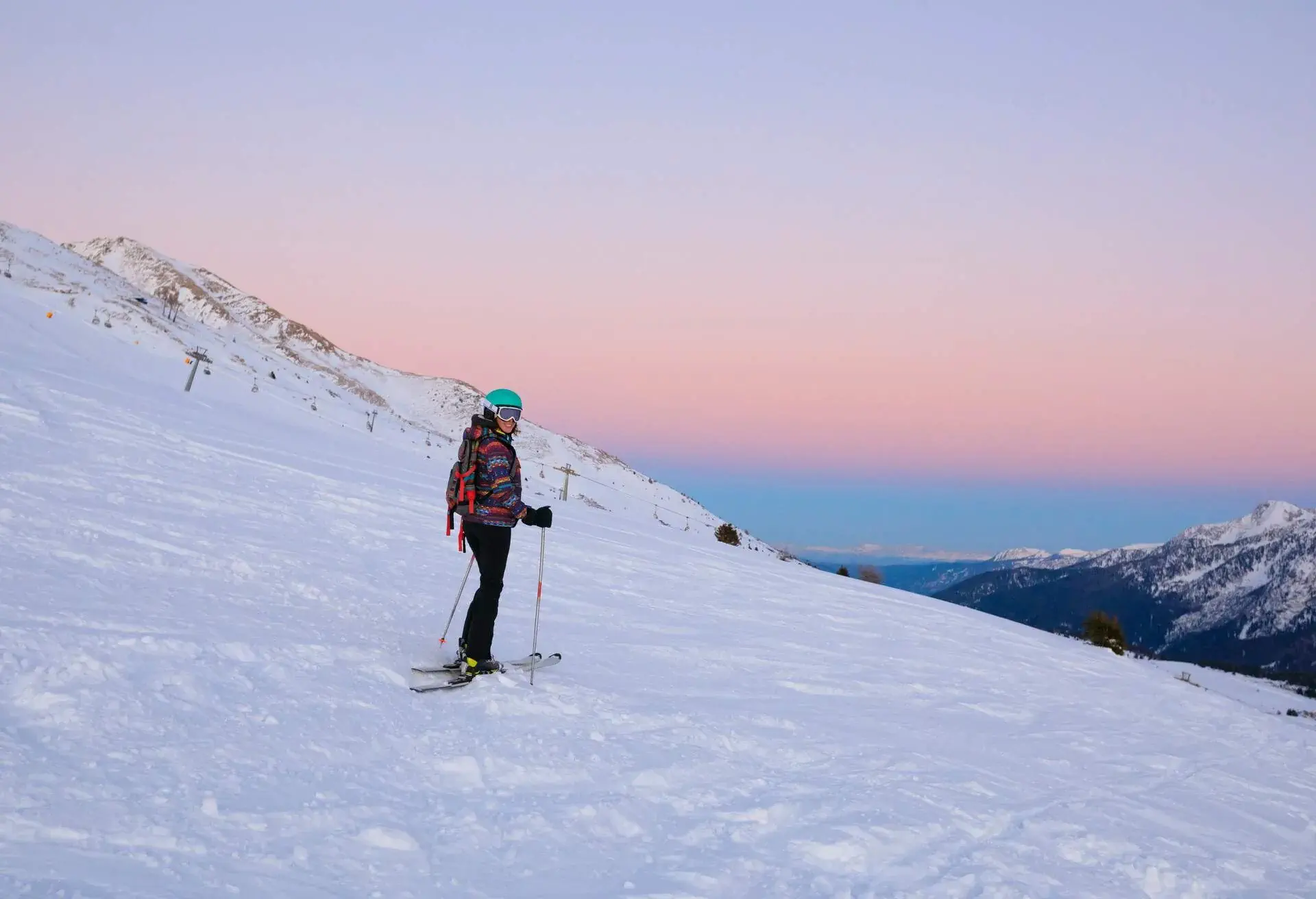 Woman skier enjoys, in a beautiful view at sunny ski resort Amateur Winter Sports. Sunset On the top. High mountain snowy landscape. Italian Alps mountain of the Dolomites Passo Tonale, Italy.