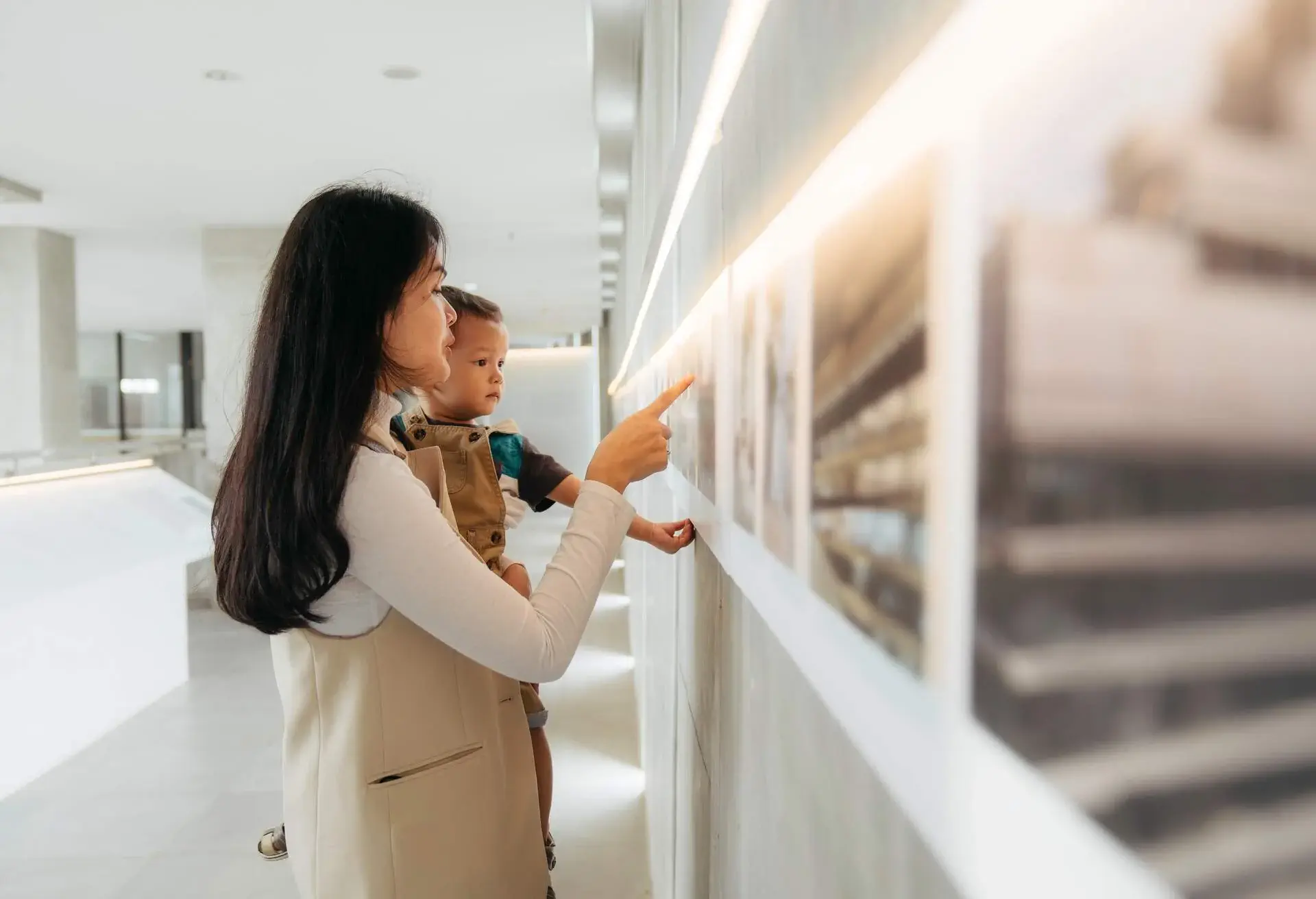 Asian women watching the exhibition with her baby in art gallery