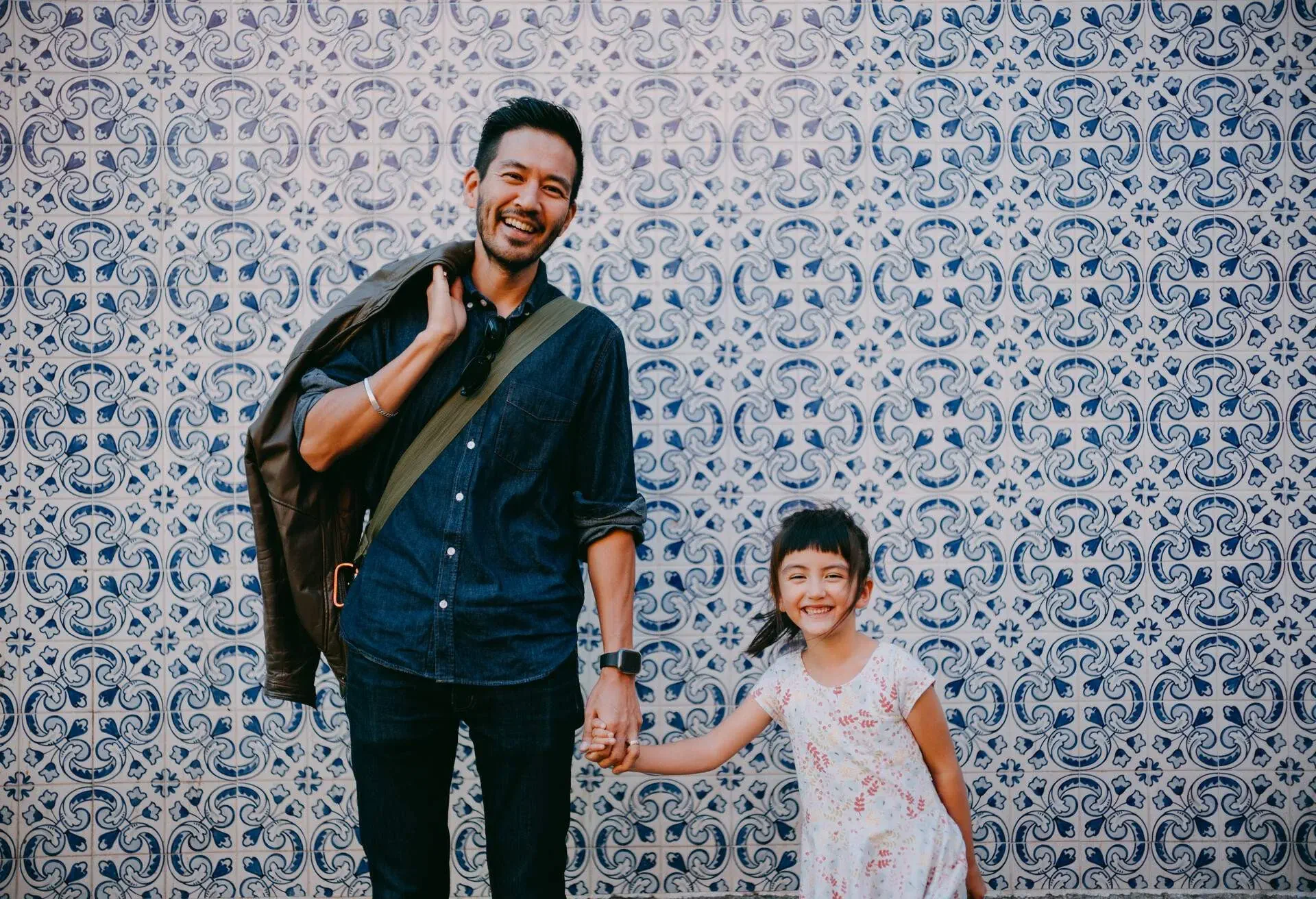 Japanese father and his preschool mixed race daughter on street of Portugal with azulejo tile wall