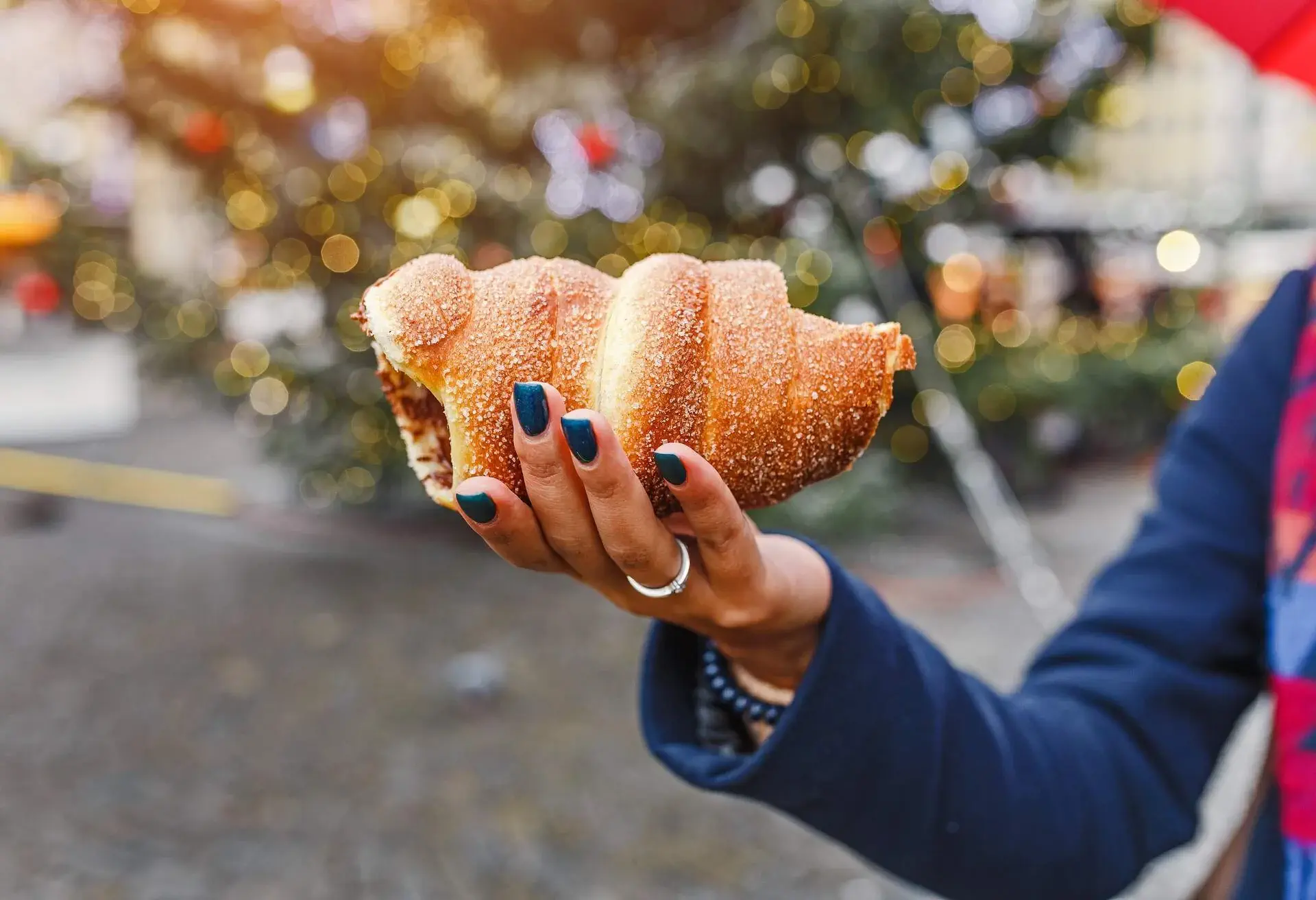 A woman with an appetite eats a traditional sweet pastry of Czech in Prague - a trdelnik on the background of a Christmas tree and a New Year's fair