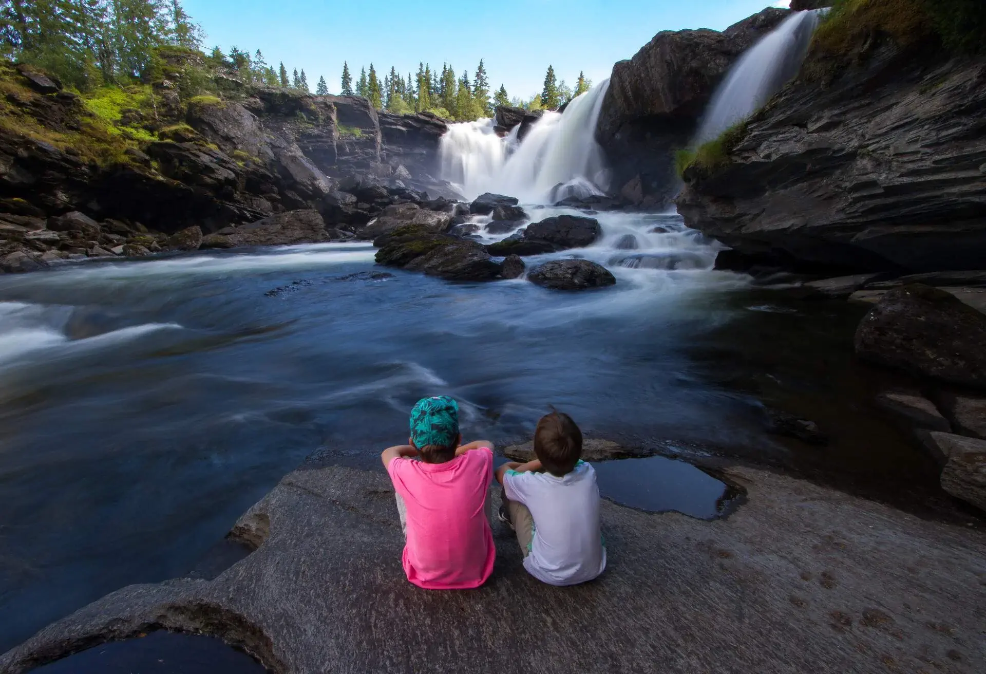 Ristafallet in Jämtland Sweden brings mindfulness to two boys sitting on a flat rock by the mesmerizing waterfalls