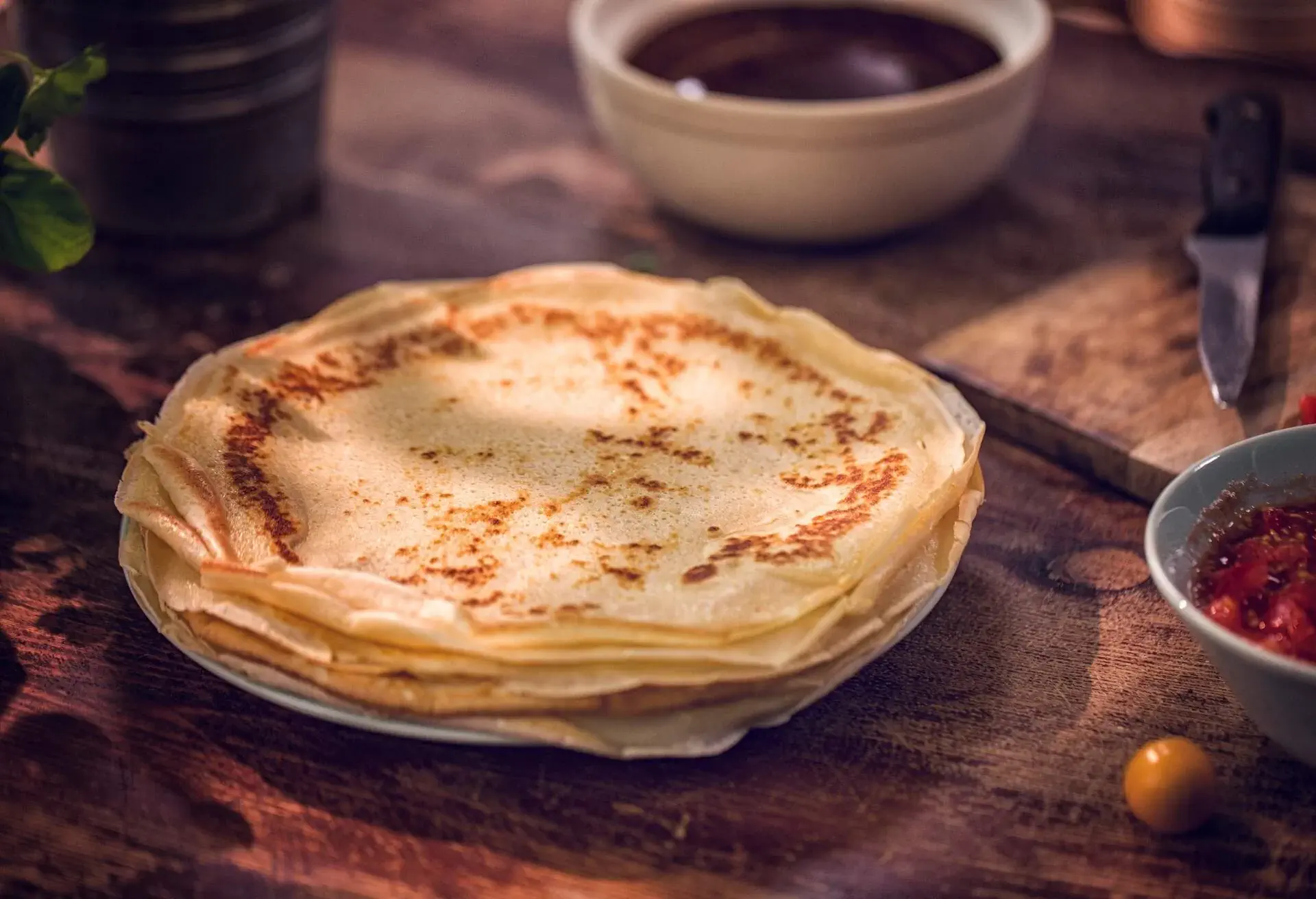 Preparing delicious crepes pancakes with ham, tomatoes and herbs baked with cheese.