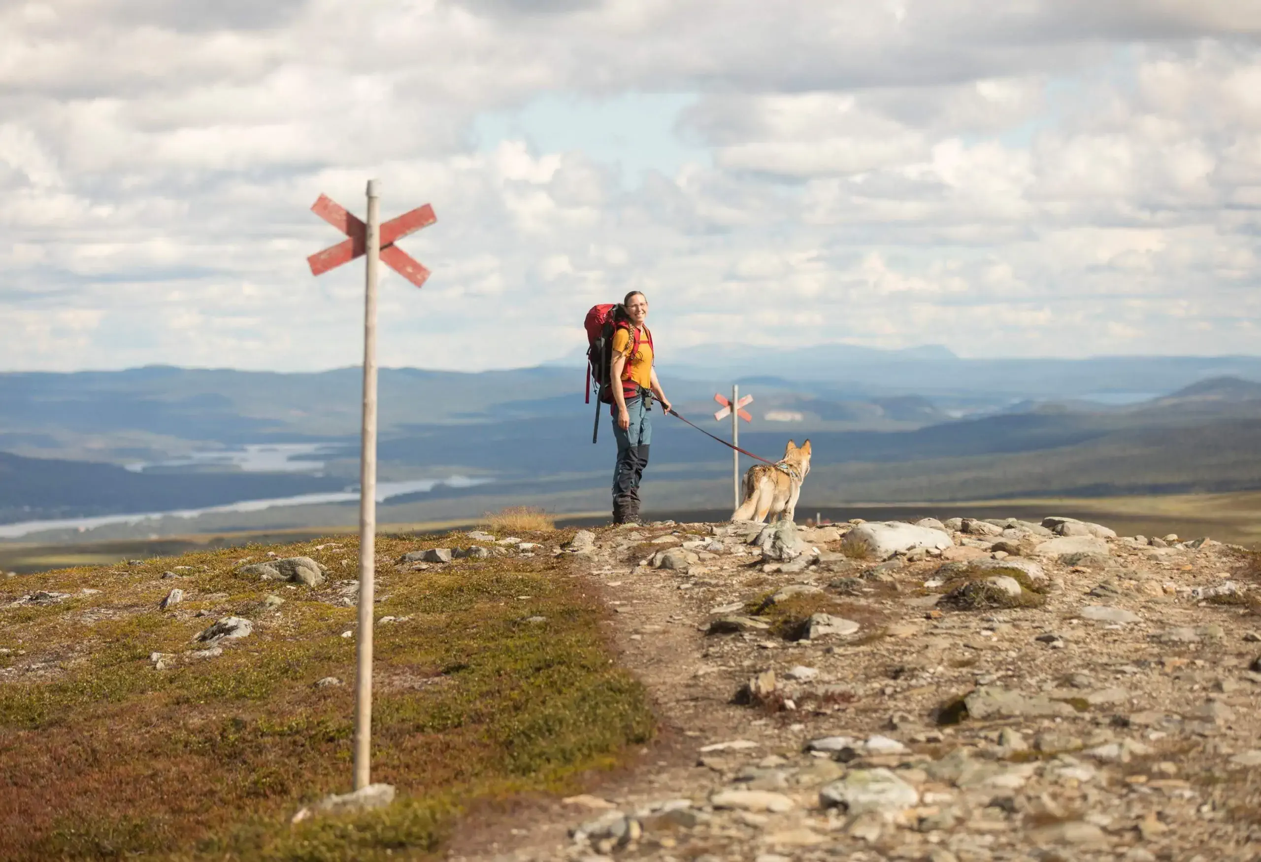 Woman wearing a backpack hiking with her dog on a mountain