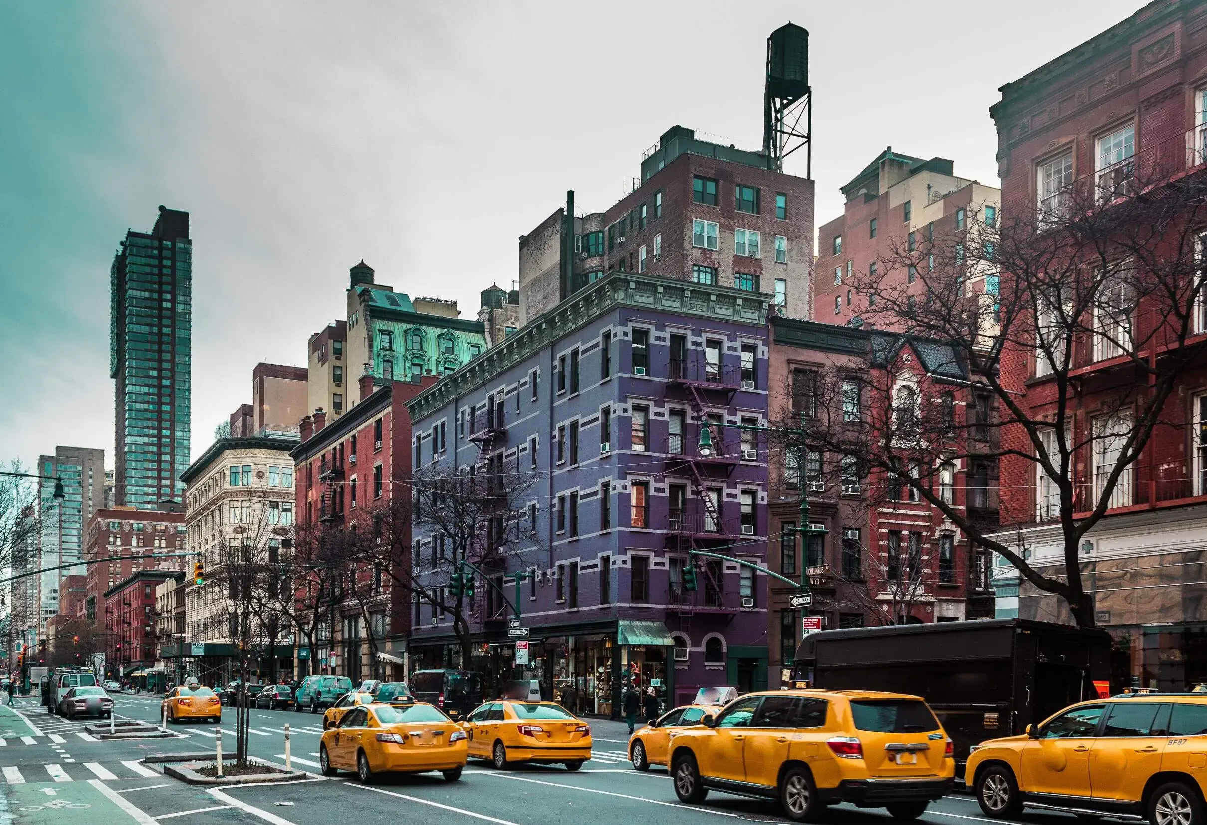 A bustling street with yellow cabs and cars lined with colourful buildings.