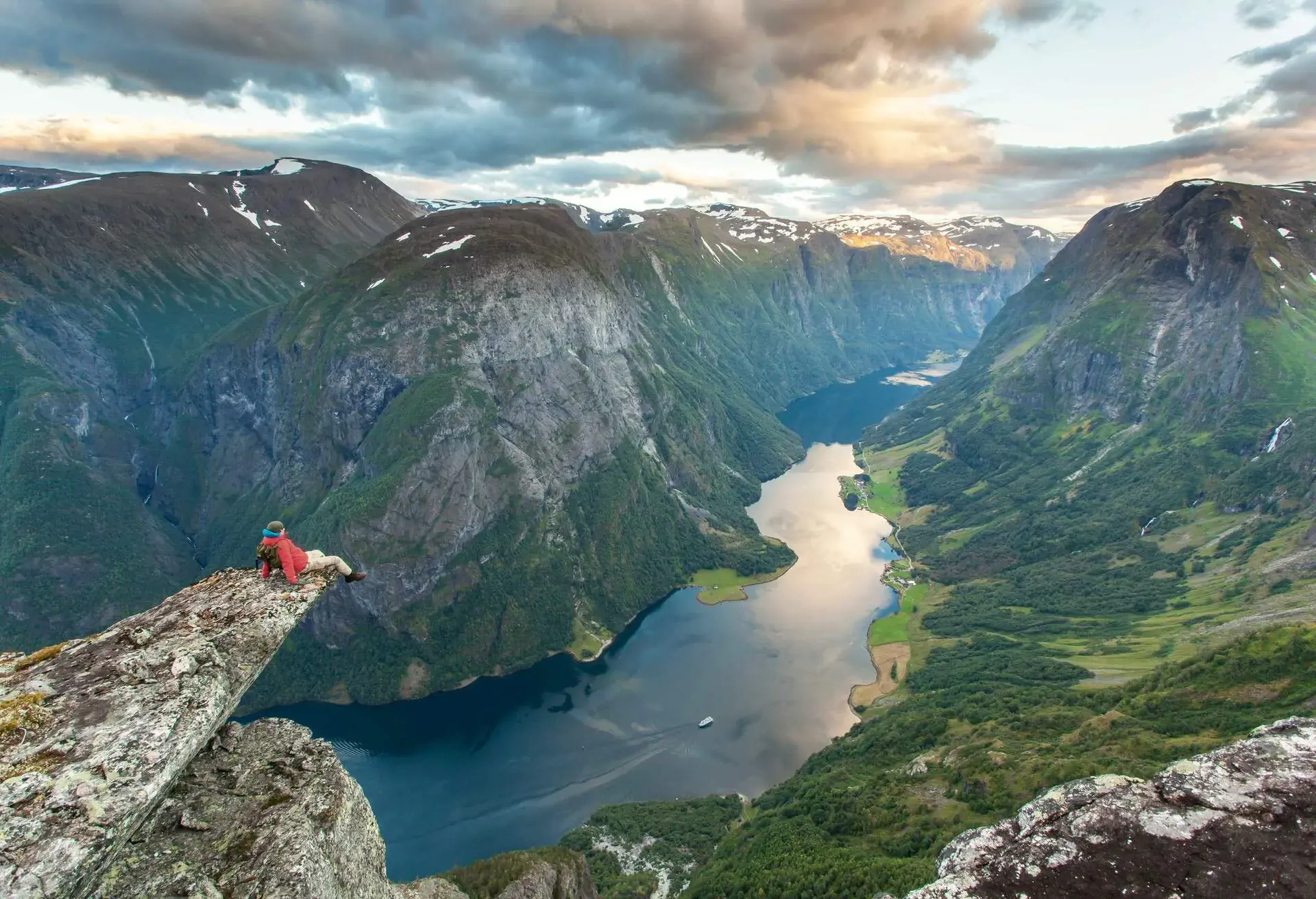 Man sitting on cliff over Naeroyfjord in Gudvangen, Norway