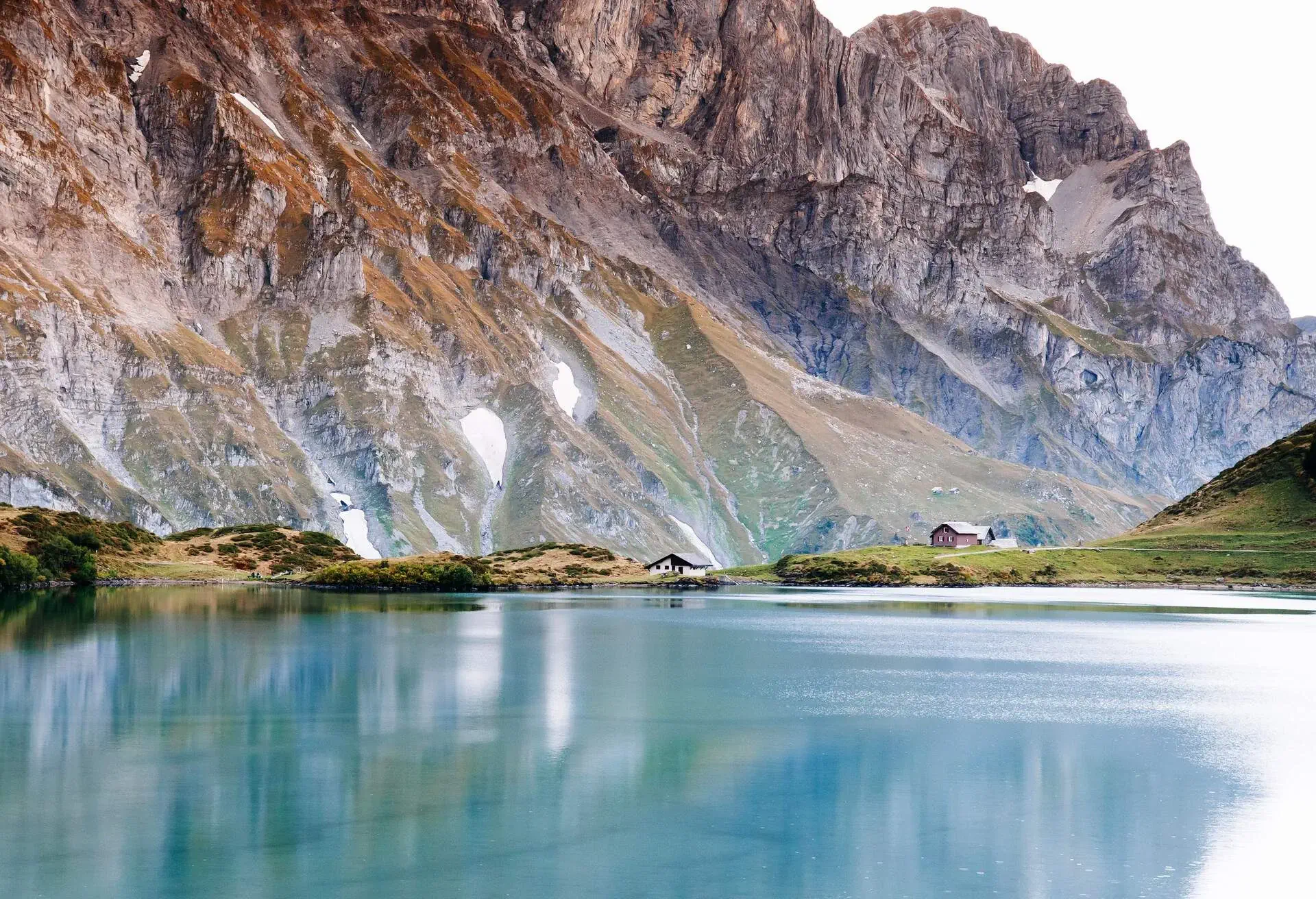 Rural landscape scenery with small cottage on Trubsee lake shore, Swiss alps Mount Graustock peak on background, foot of mount Titlis in Engelberg