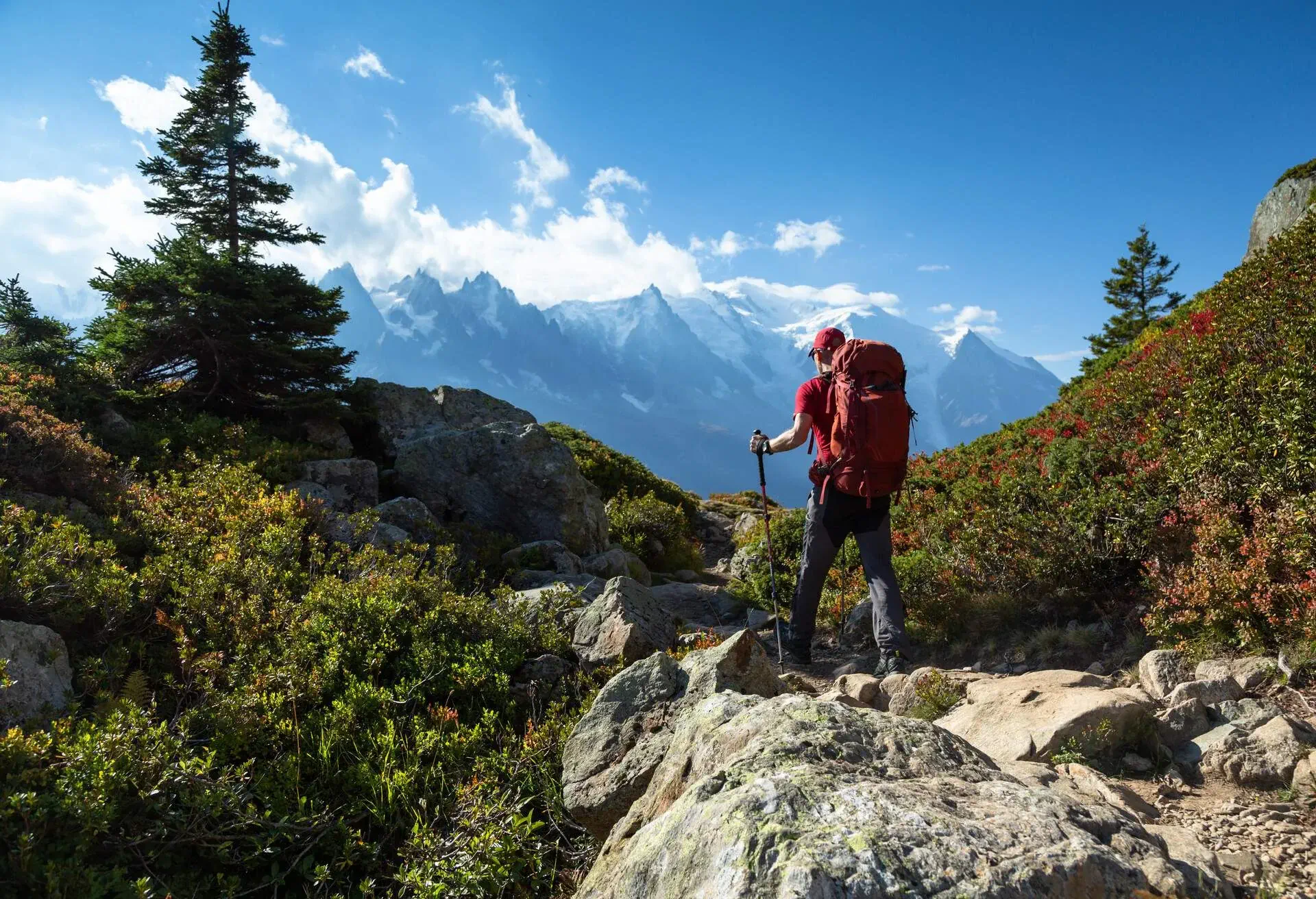 A backpacker walking on a rough terrain in the mountains.