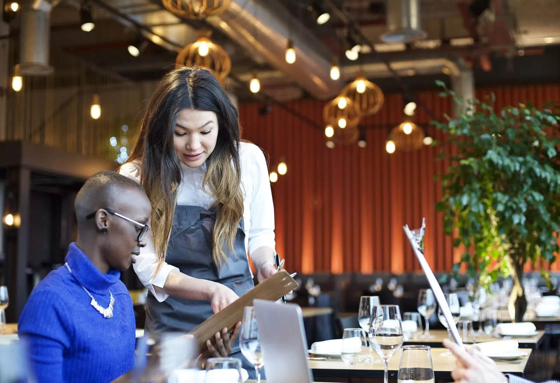 Waitress explaining menu items to a woman in a restaurant