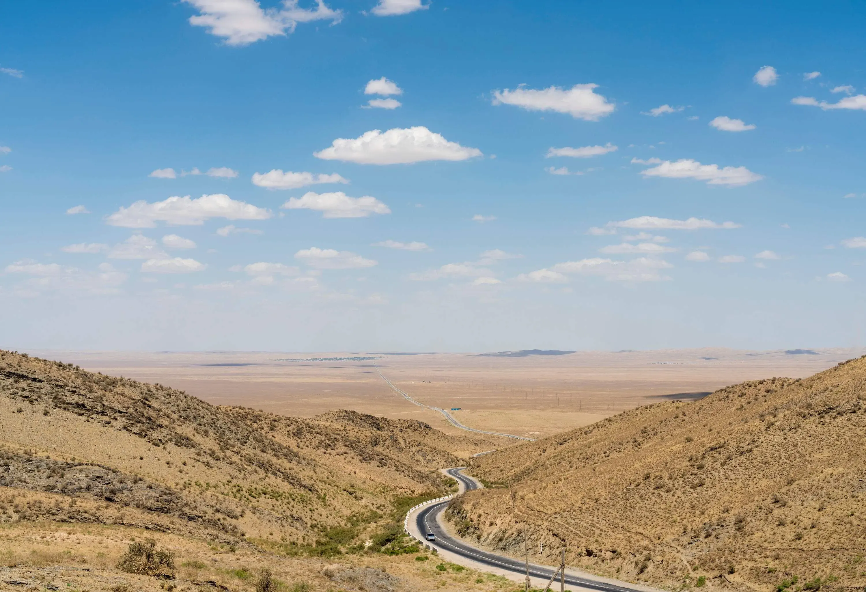 A winding road across a deserted valley under clear skies.