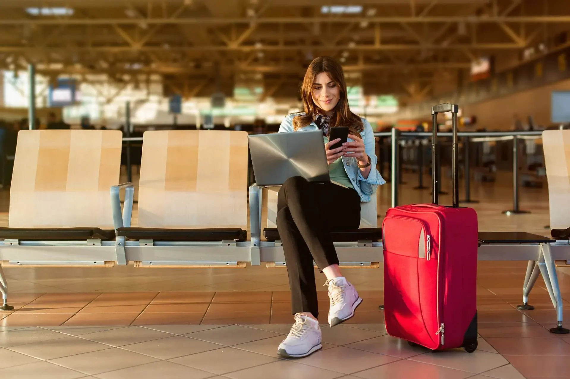 A woman sitting at the airport and looking at ther mobile phone