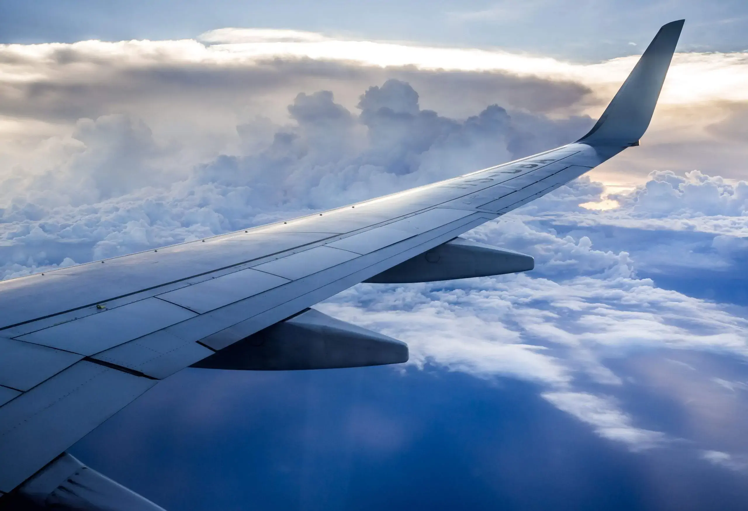 An airplane wing above a sea of clouds.