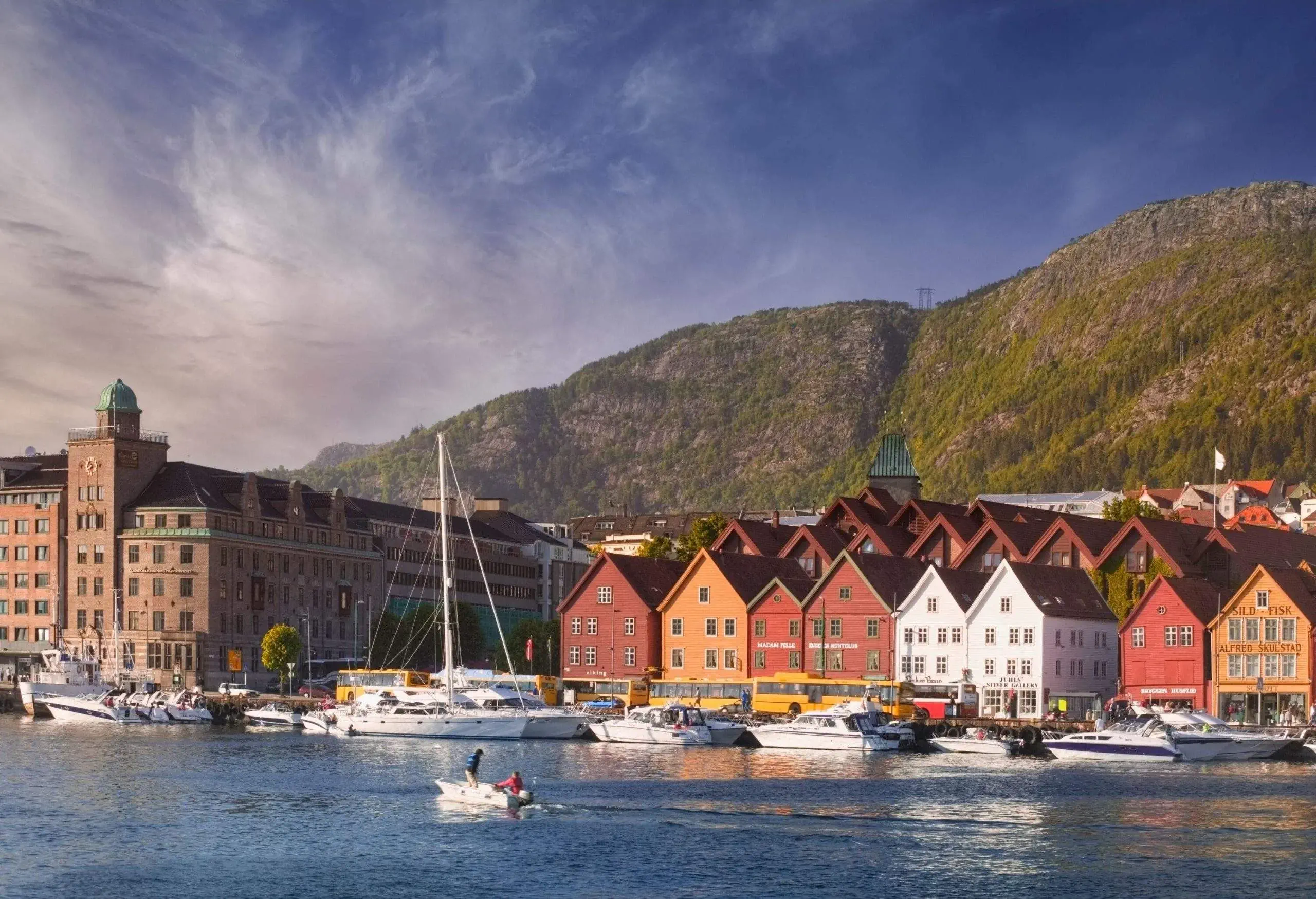 Compact, colourful buildings and houses on the mountain's foot surround the boats docked on the harbour.