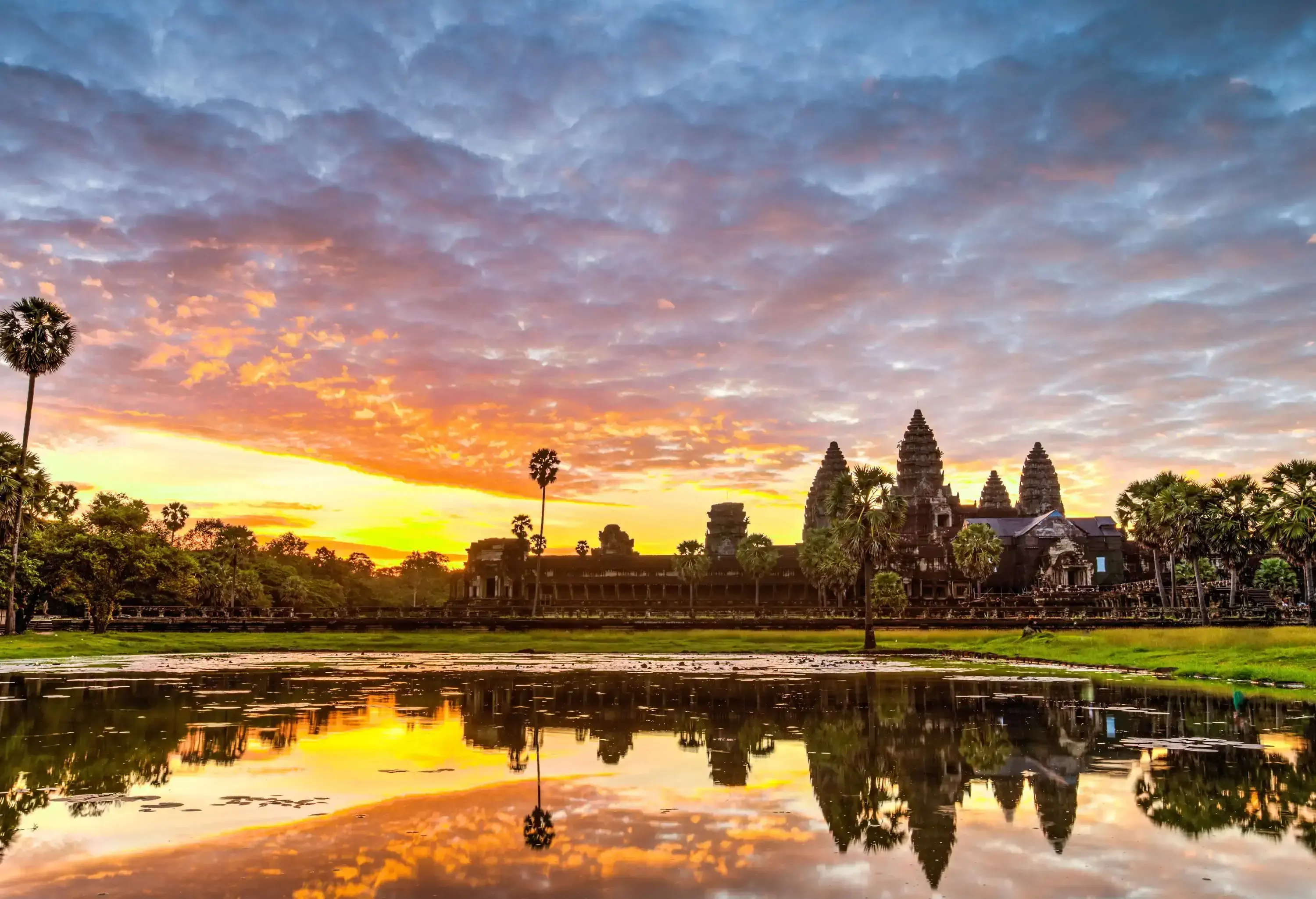 A reflective marsh displaying Angkor Wat's outline and the golden hue of light that sweeps over the sky.