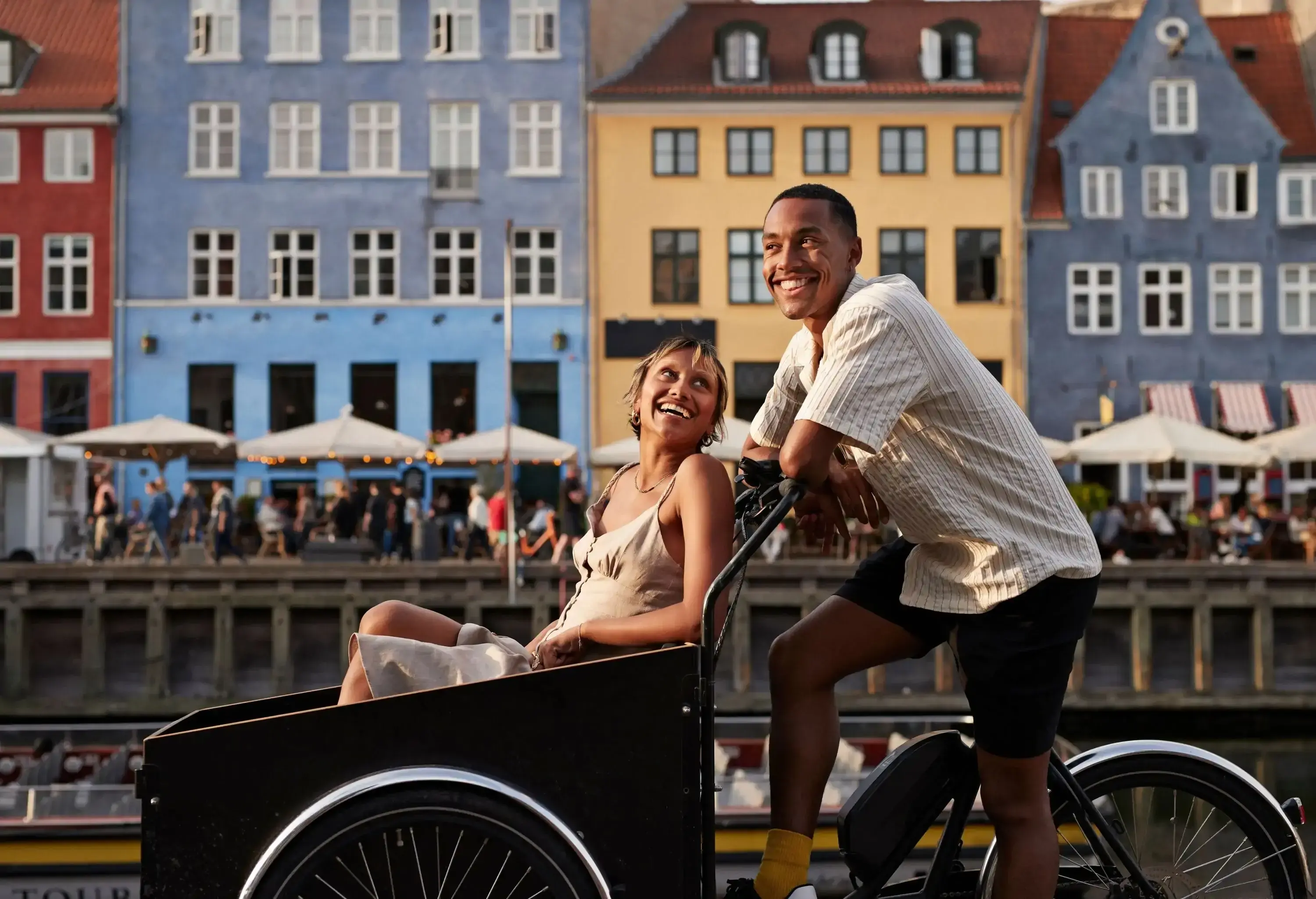 Happy young man with girlfriend in cargo bike at famous pier