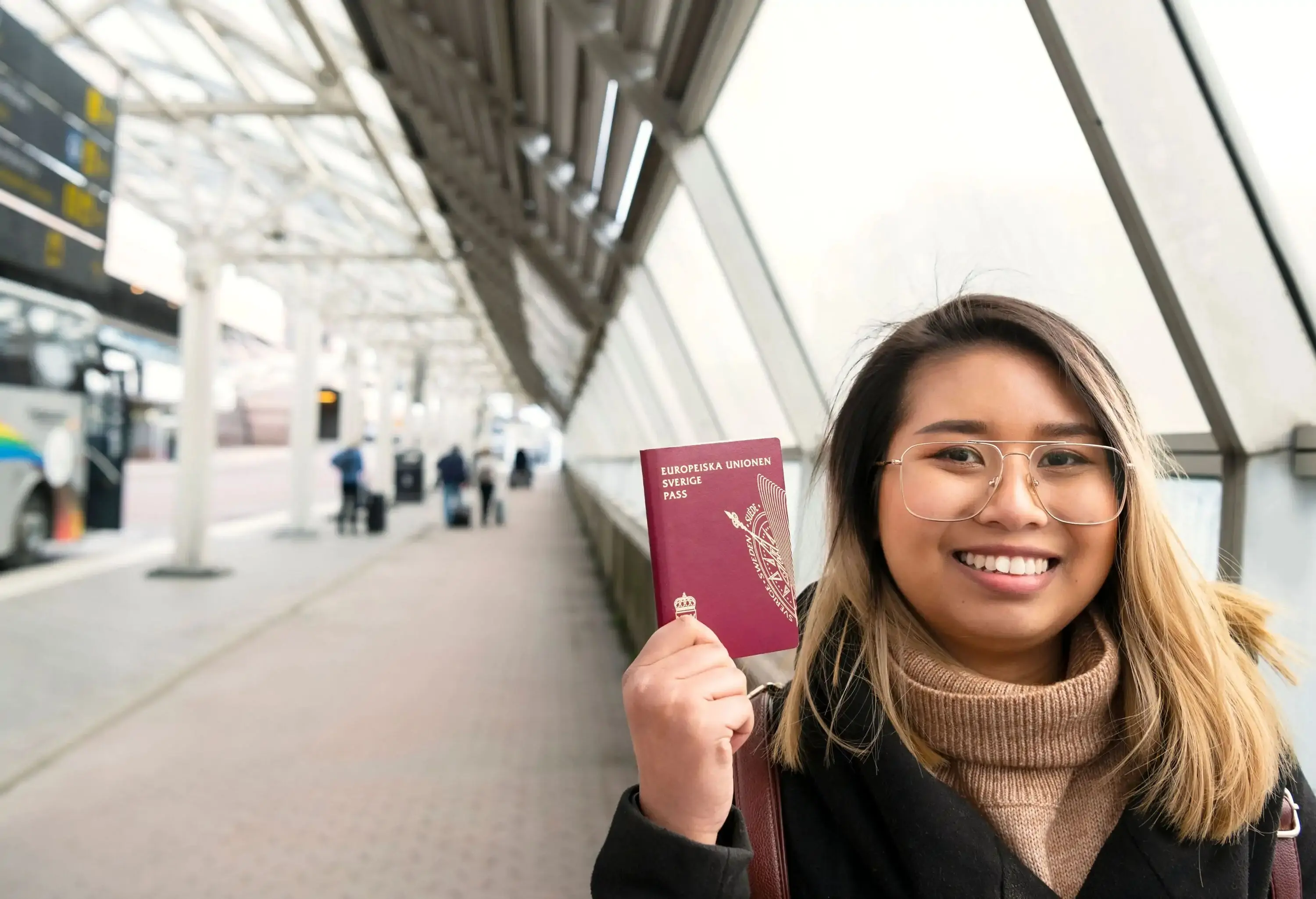 Woman at the airport smiling and showing her Swedish passport