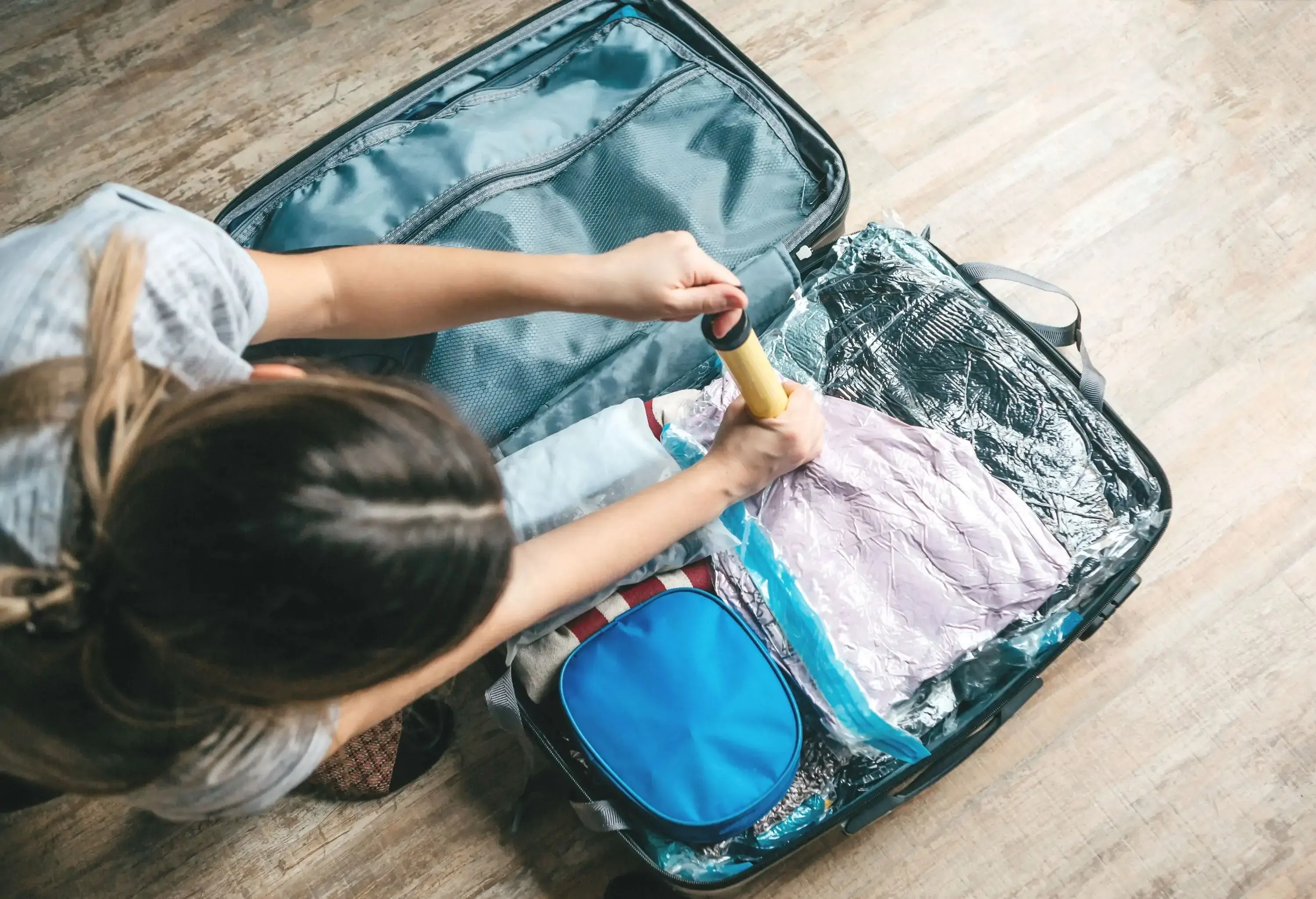 A girl packs things or clothes with a vacuum pump to save space in a travel suitcase.