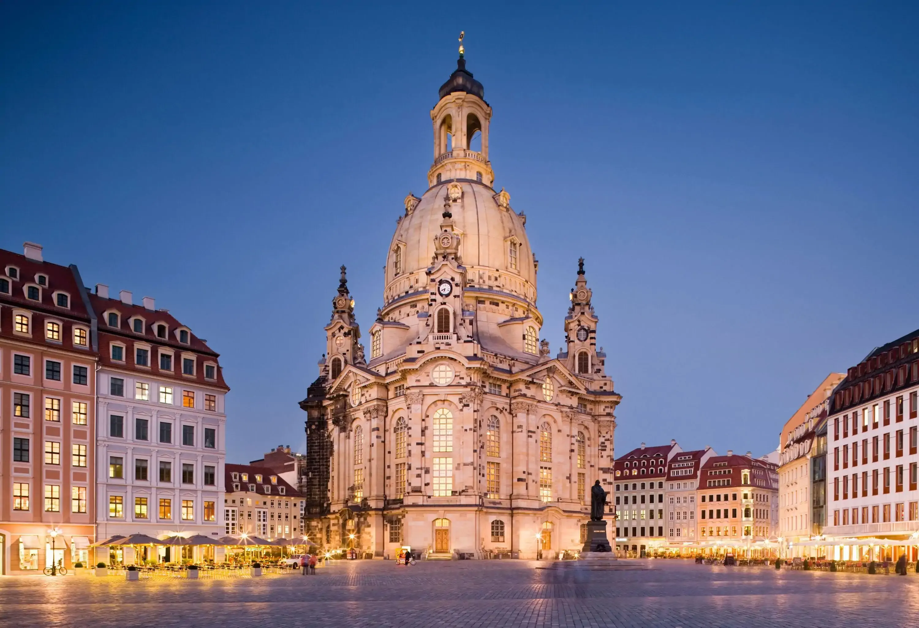 A picturesque enormous dome church lined with buildings on a vast cobbled square.