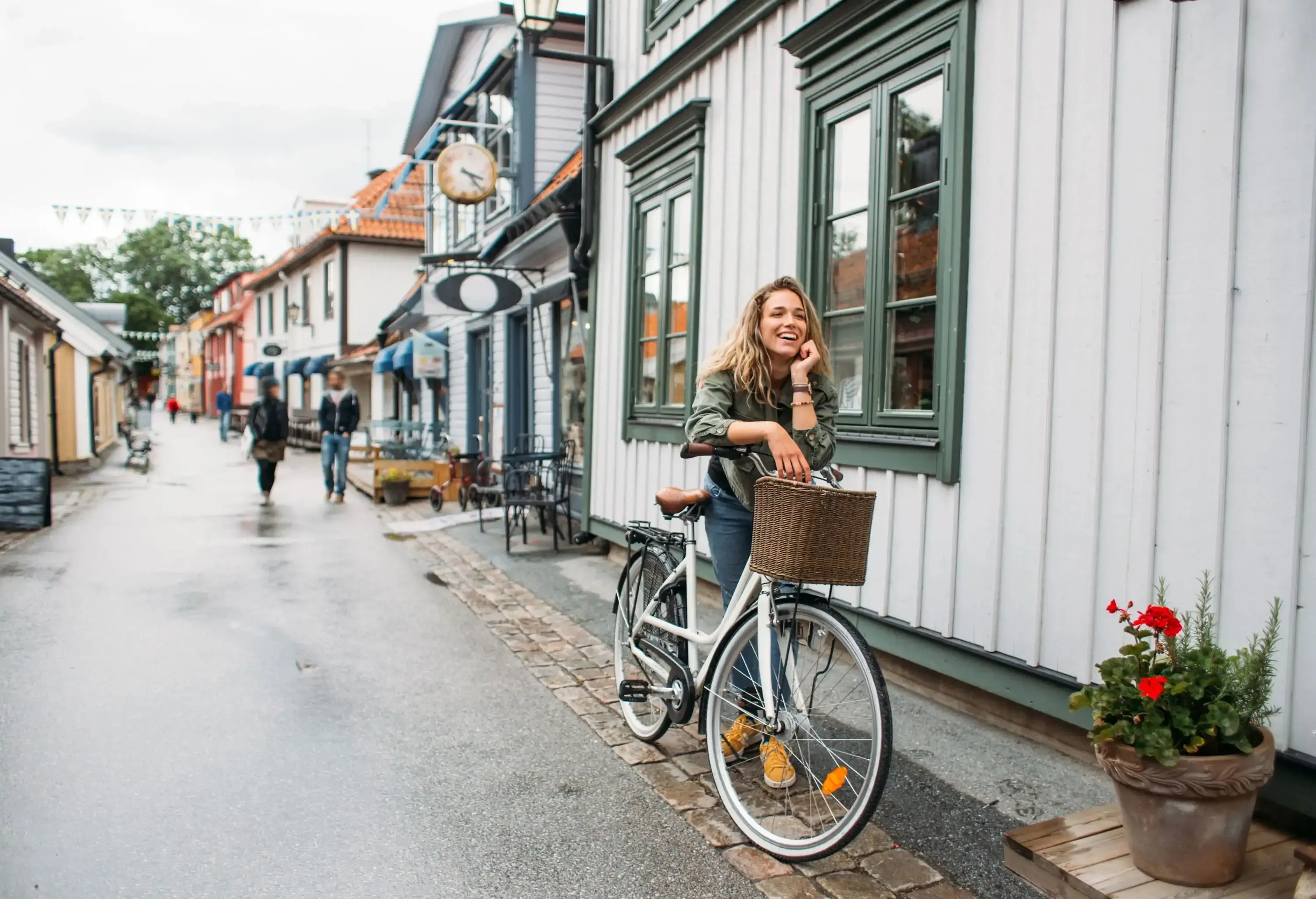 Modern carefree female tourist visiting Sigtuna while relaxing on her white bicycle