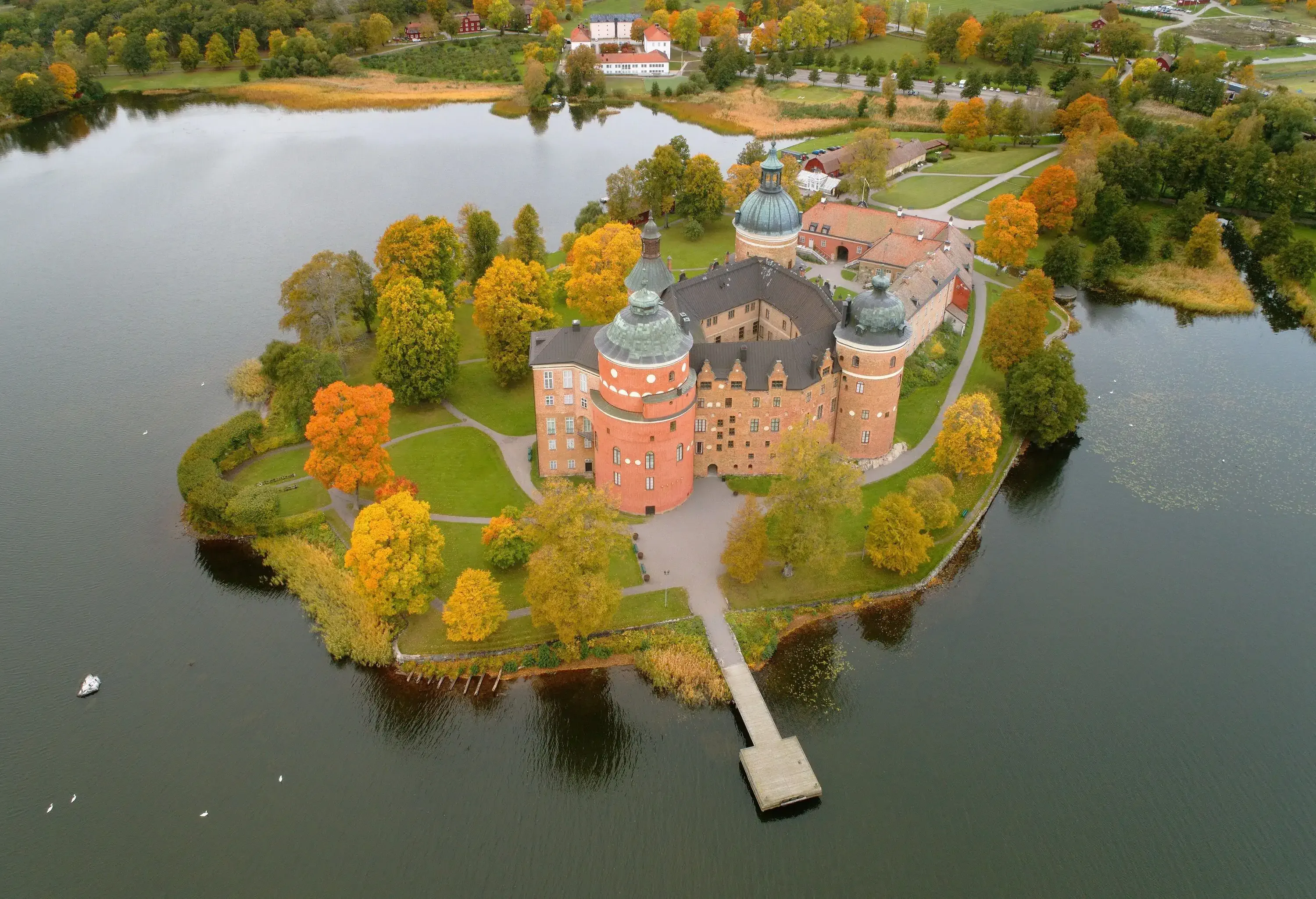 Renaissance castle near a lake, framed by vibrant fall foliage.