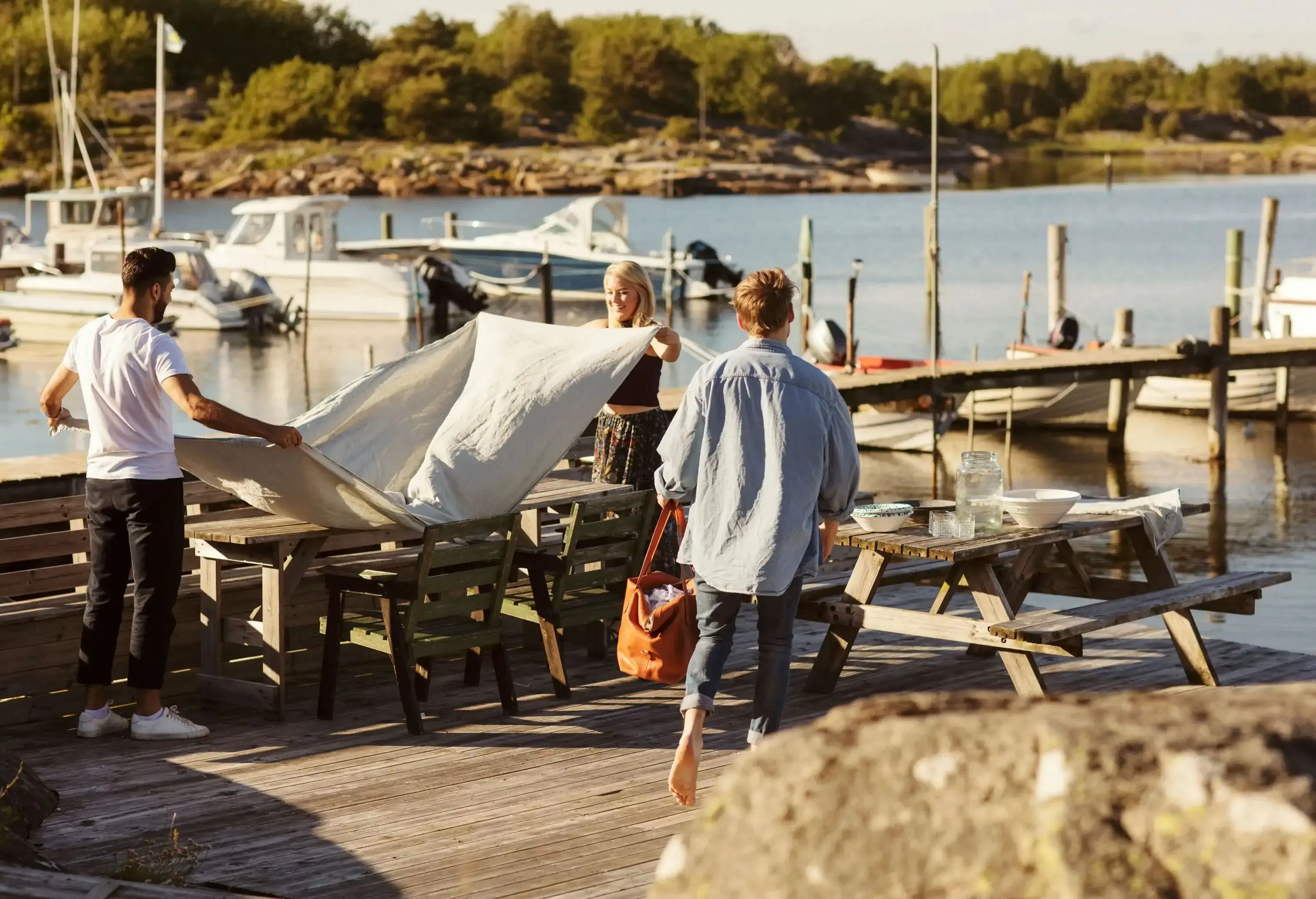 People setting up a picnic table on a deck by the sea.