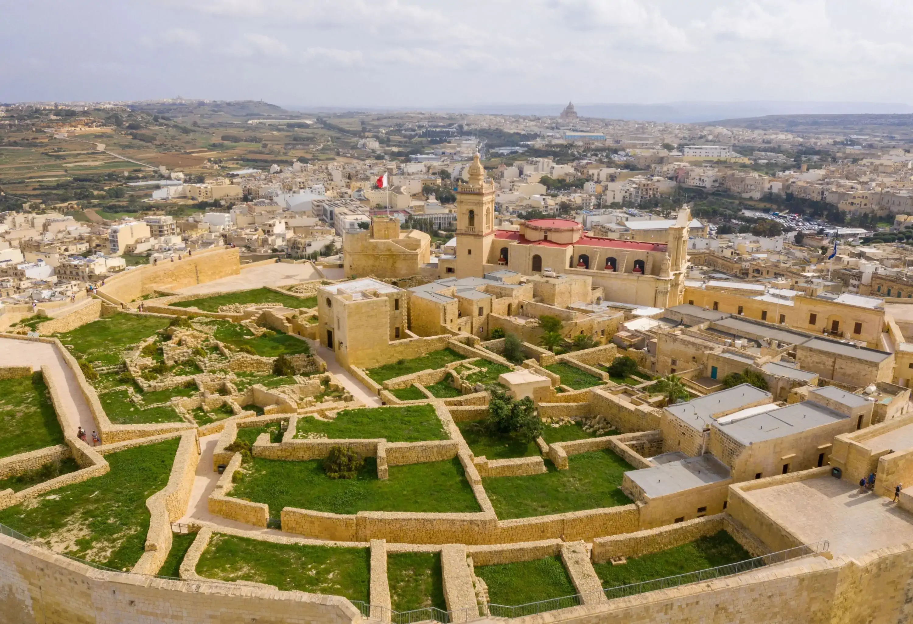 A medieval fortress with ruins of stone walls and overlooking views of the city's urban landscape.