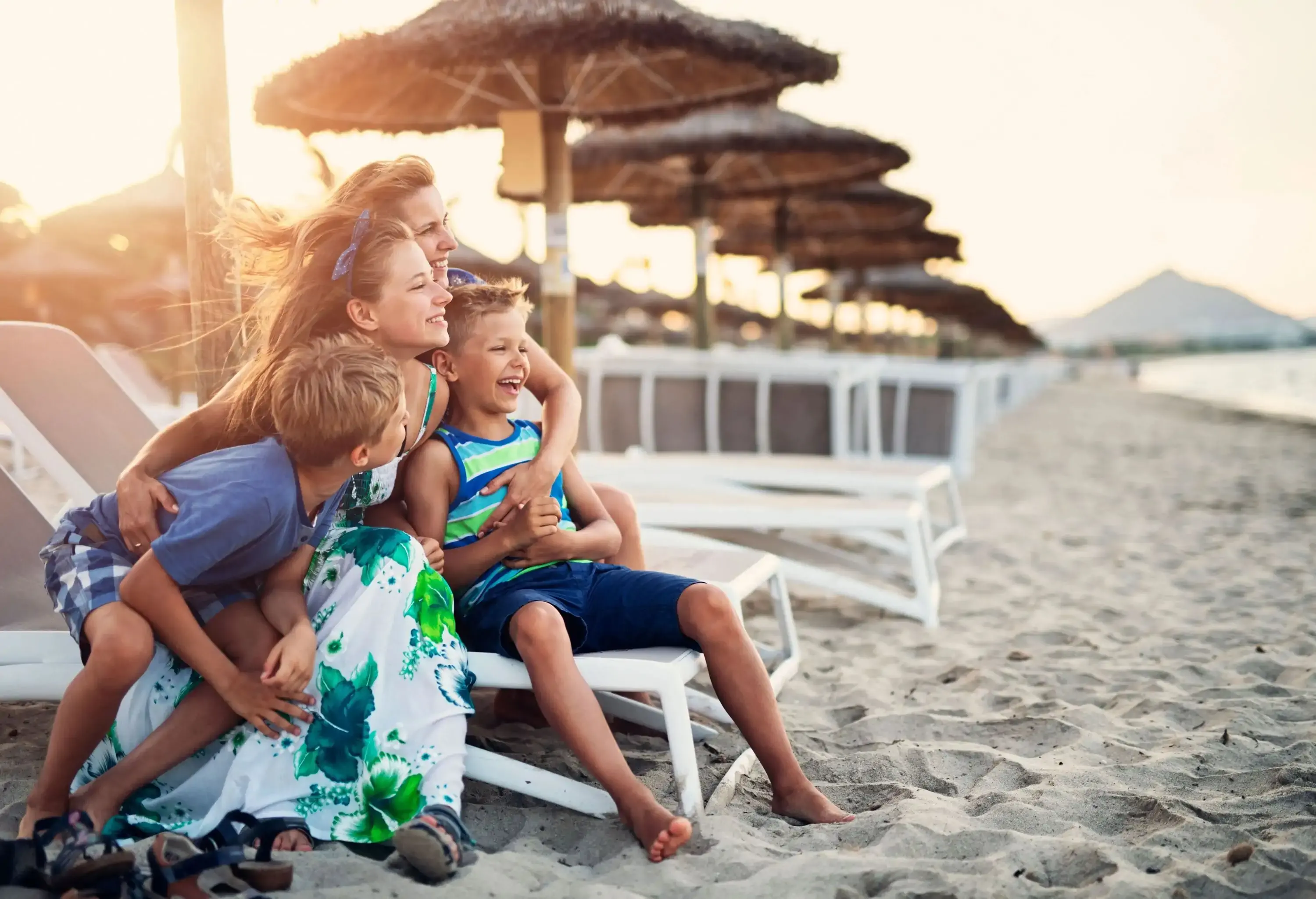 A family sitting and laughing on a sun lounger as they gaze out towards the sea.