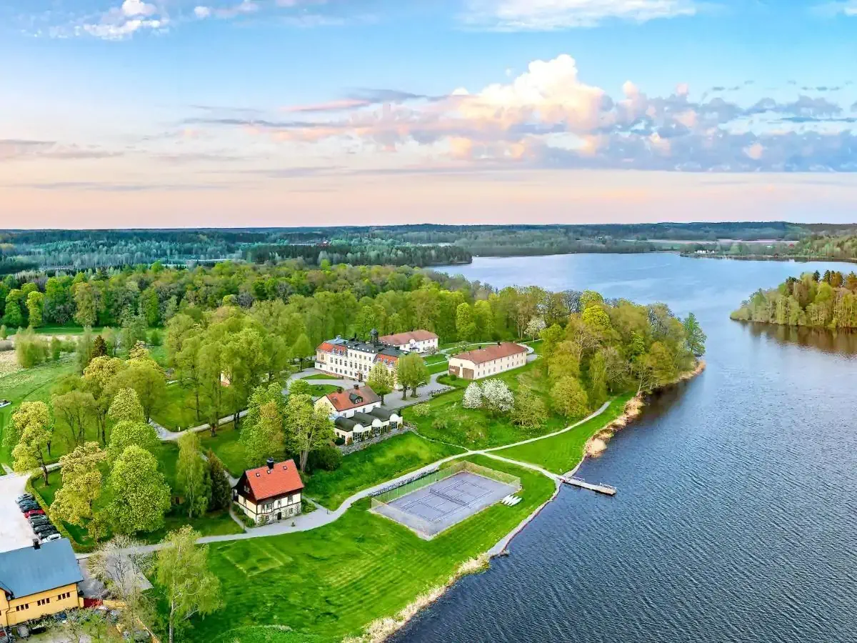 Aerial view of a castle surrounded by greenery by a lake