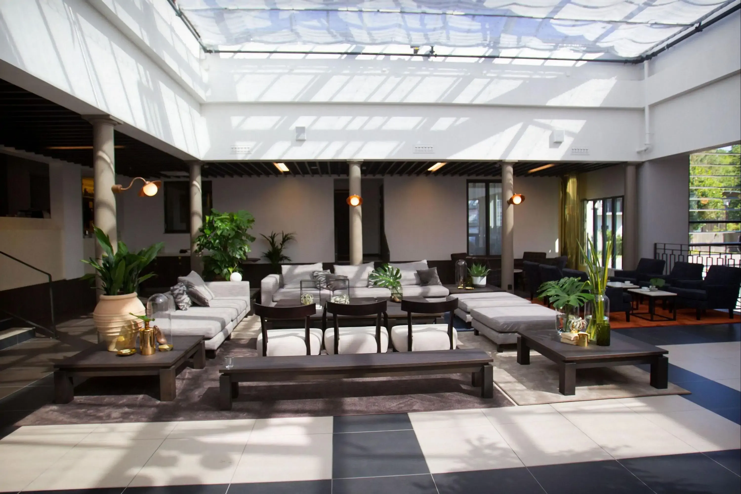 Luxury, modern hotel lobby with sunlight shining through glass roof