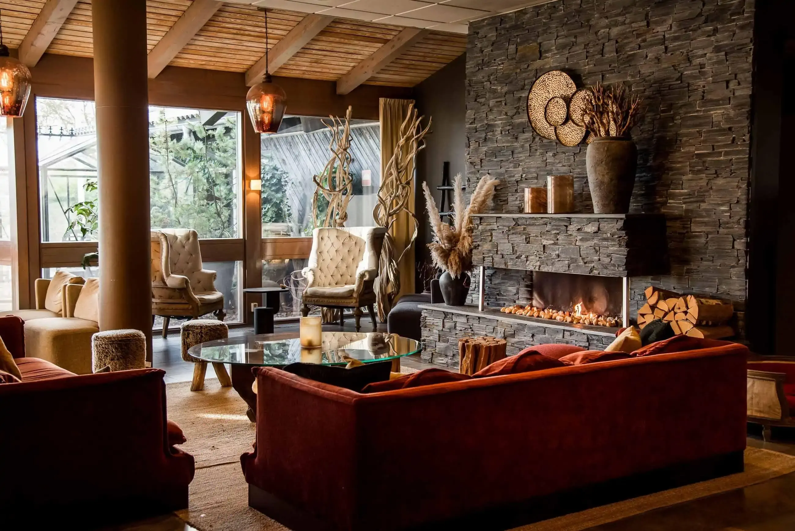 Hotel lobby decorated in rustic style wirh lit fireplace in the centre of the room