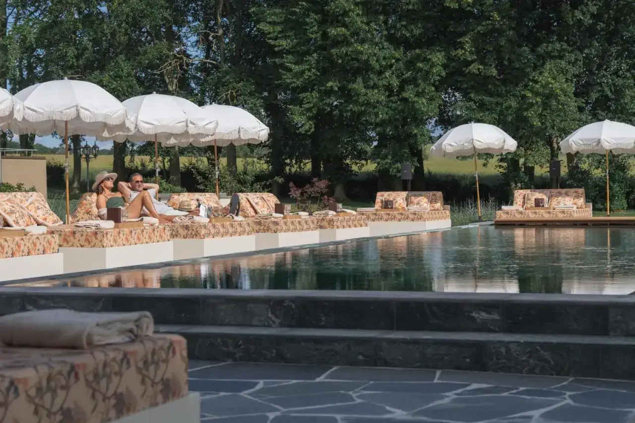 Couple laying on sunbeds by the outdoor pool of a luxury hotel