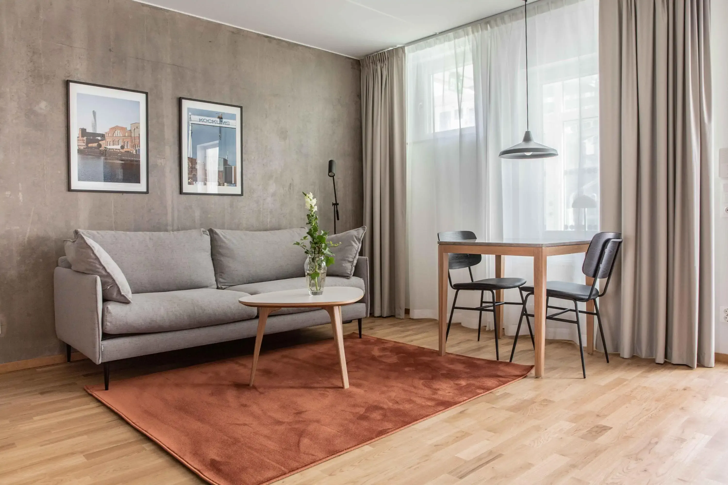 Industrial style living room in hotel with rust coloured rug and grey walls