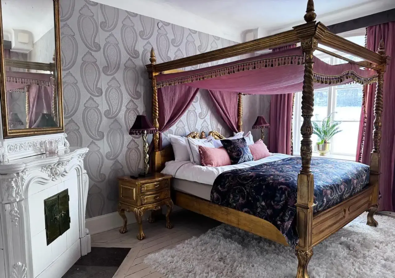Lavish hotel room of a castle stay with a gilded four-poster bed by a window